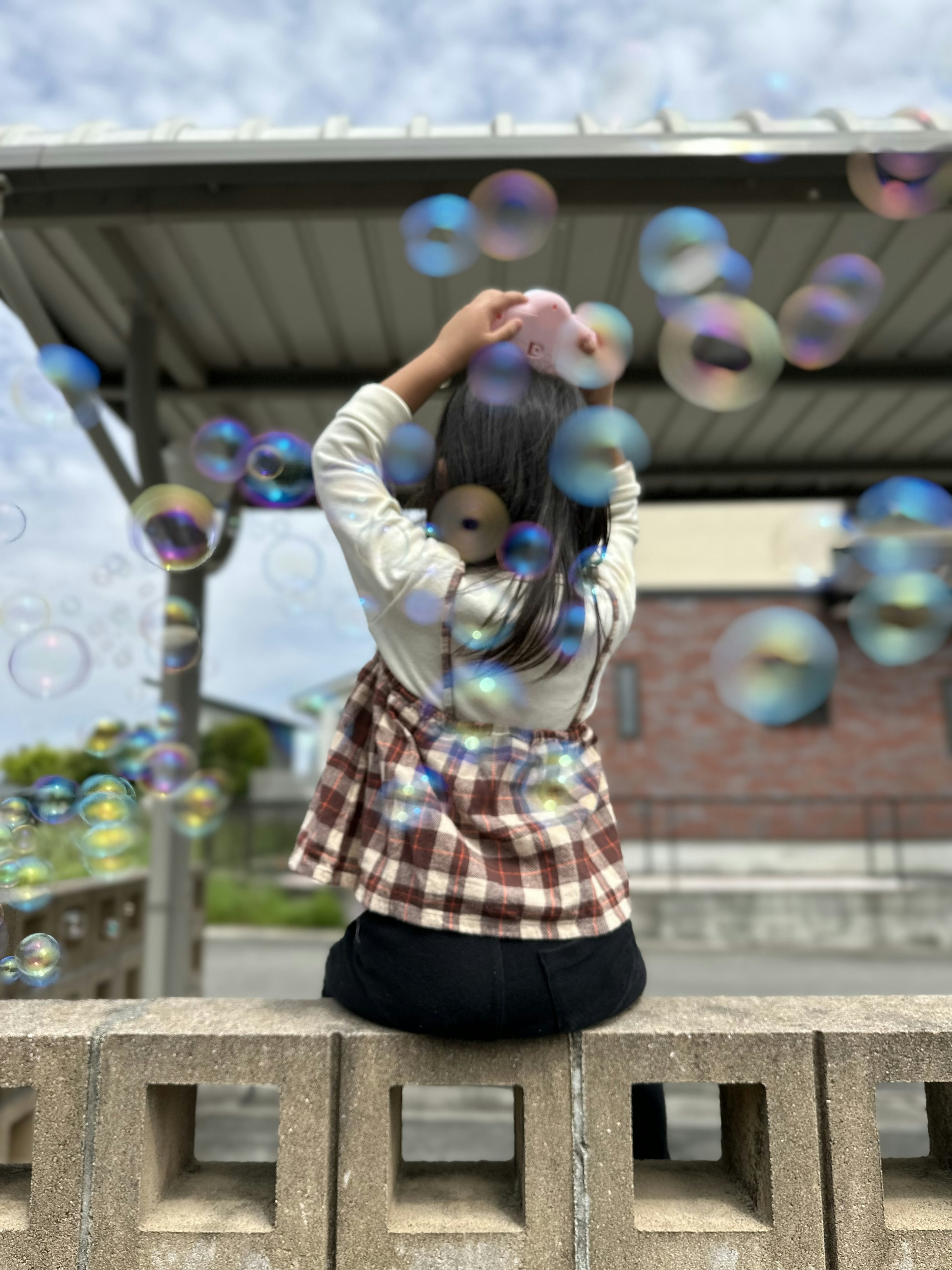 A girl sitting on a bench creating bubbles with her hands