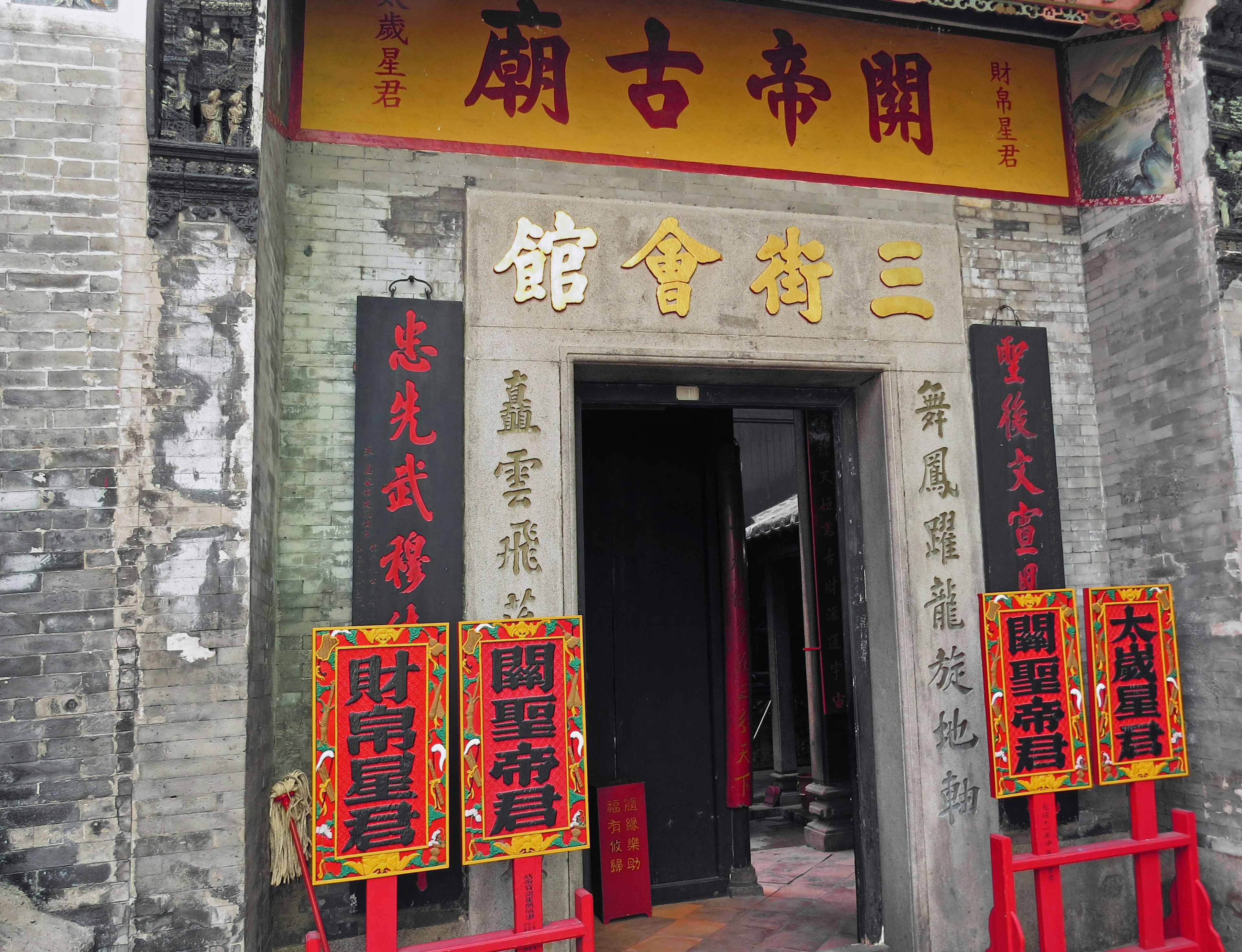 Entrance of an ancient building featuring red decorations and gold lettering