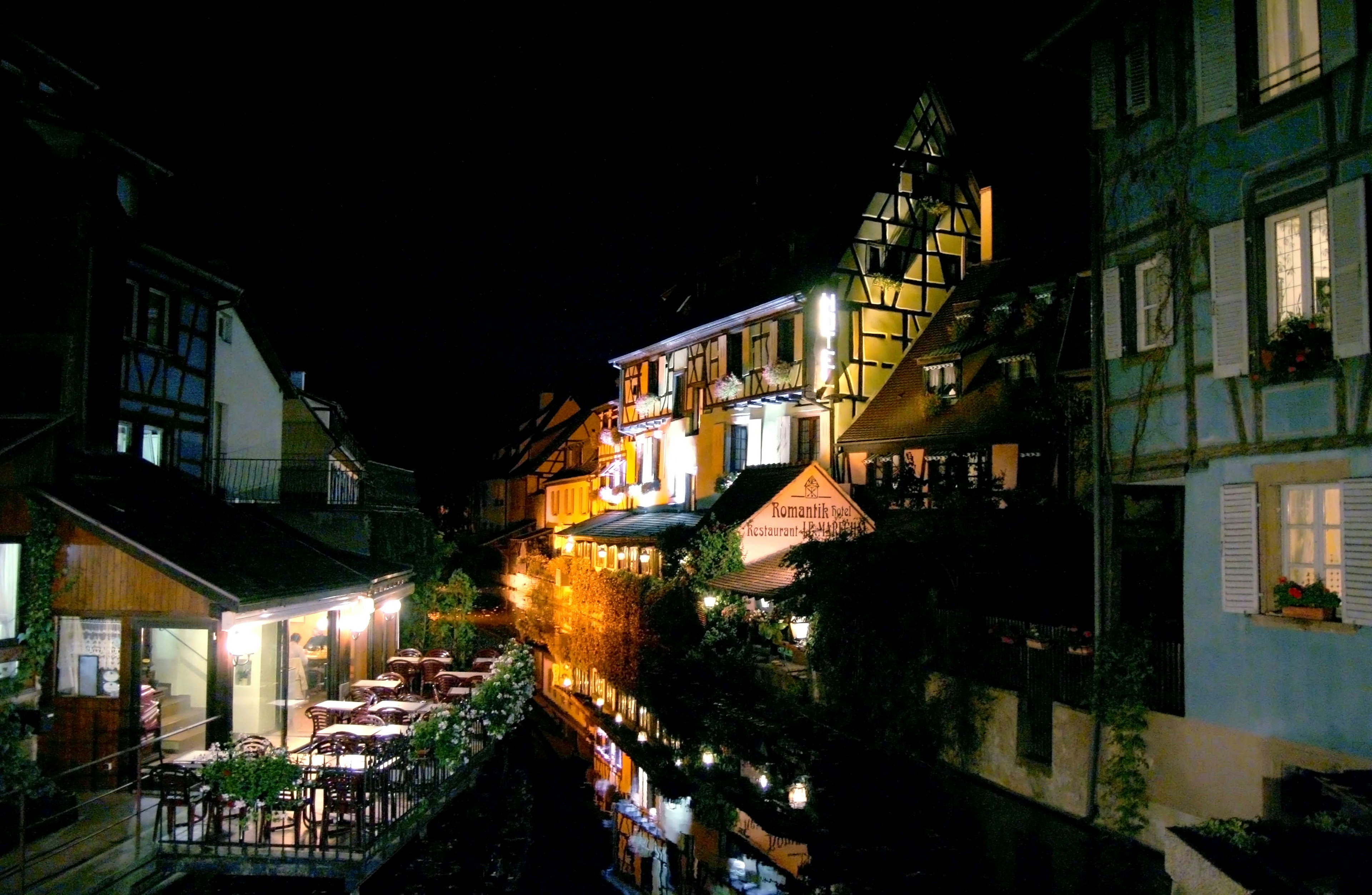 Charming riverside buildings illuminated at night with warm lights and outdoor seating