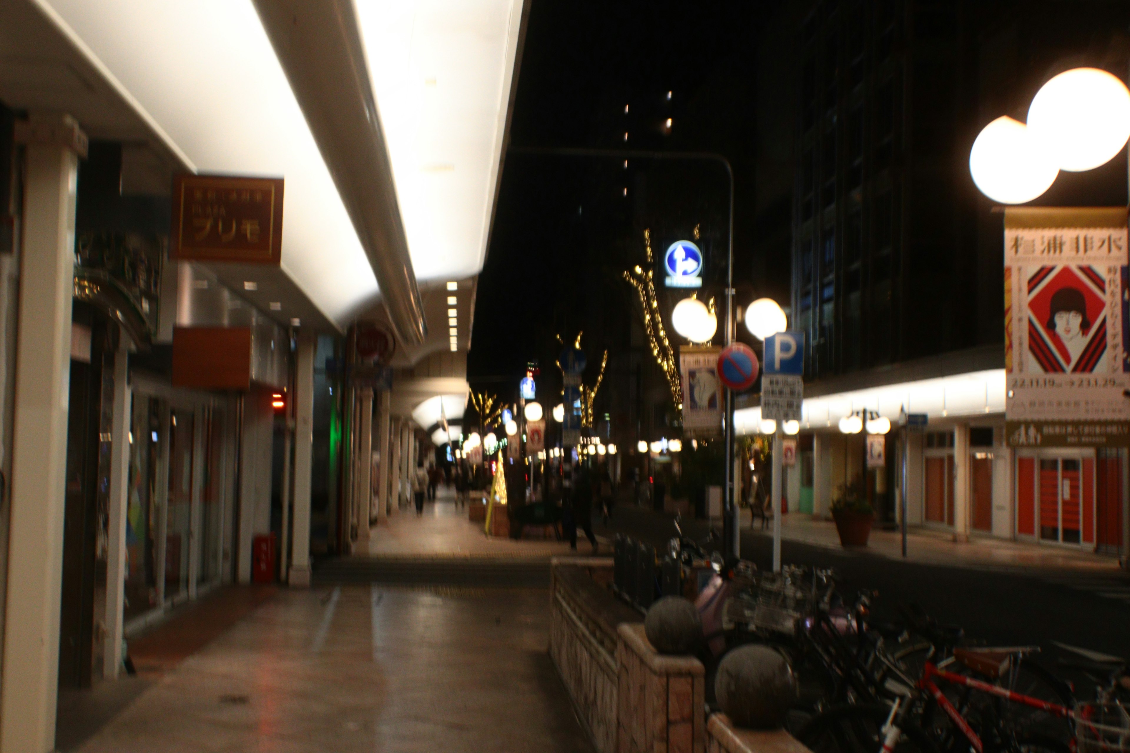 Vue nocturne d'une rue commerçante avec des magasins et des lampadaires lumineux