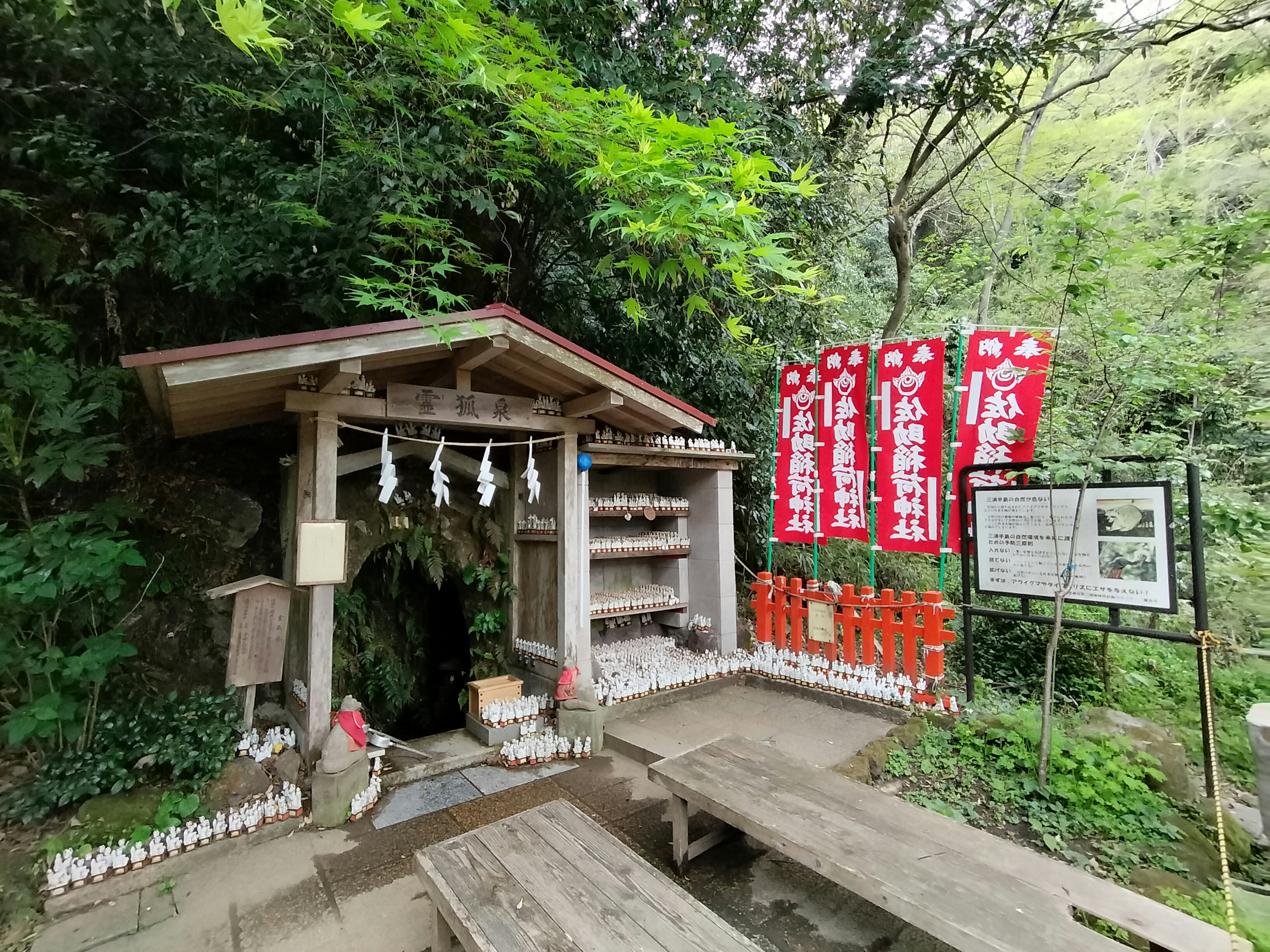 Small shrine surrounded by greenery with red banners