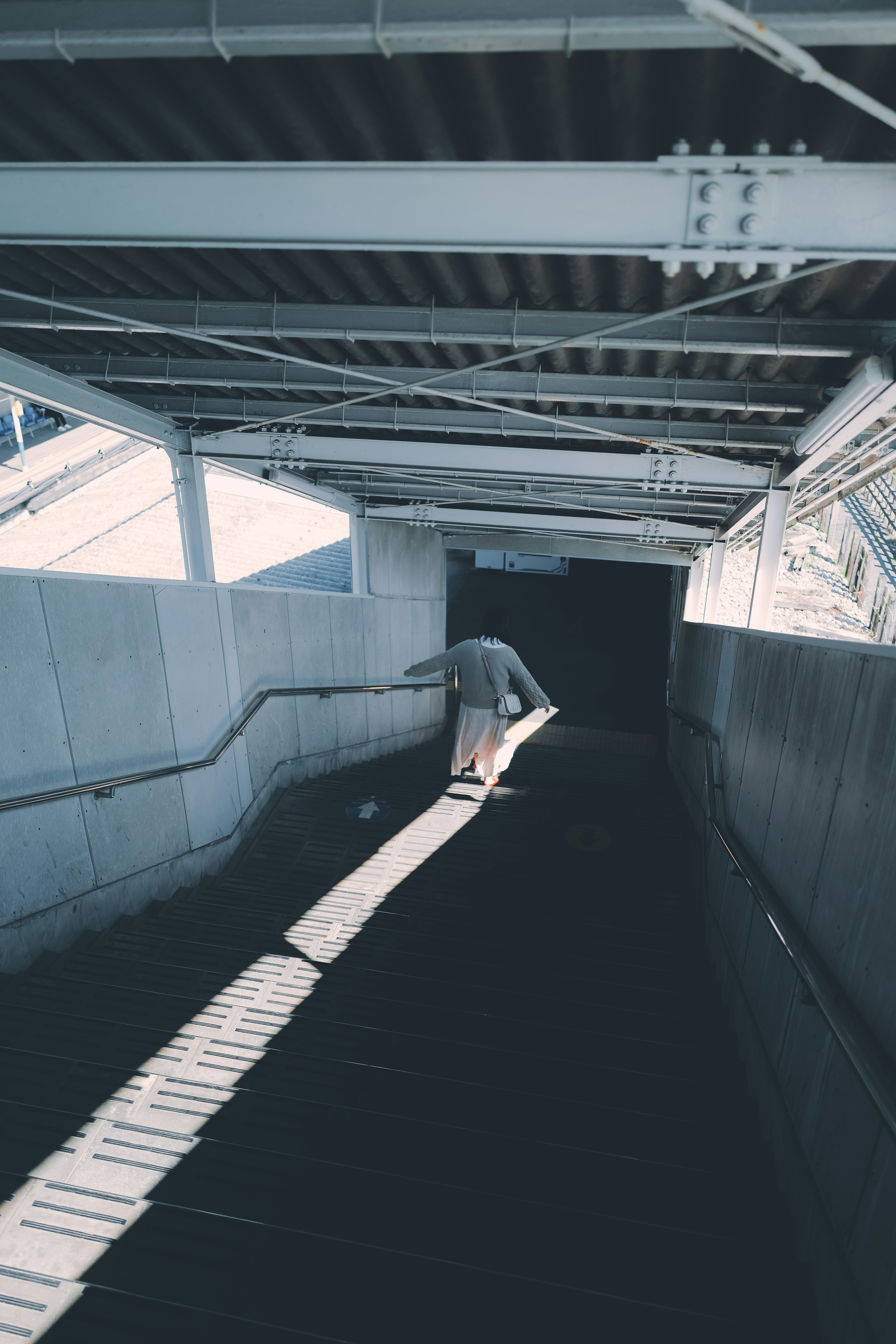 Personne marchant dans un passage souterrain faiblement éclairé avec de longues ombres