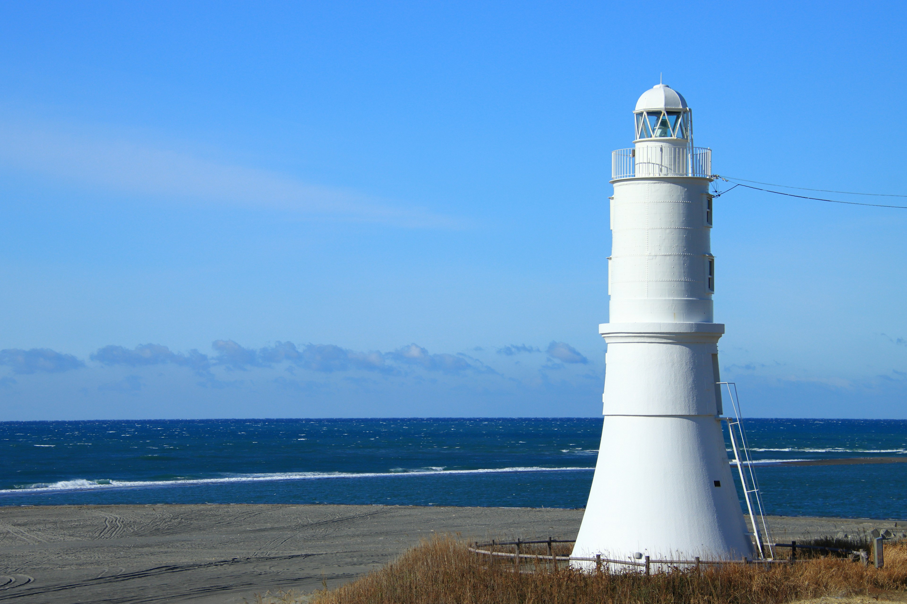 Un faro blanco se erige contra un fondo de mar y cielo azules