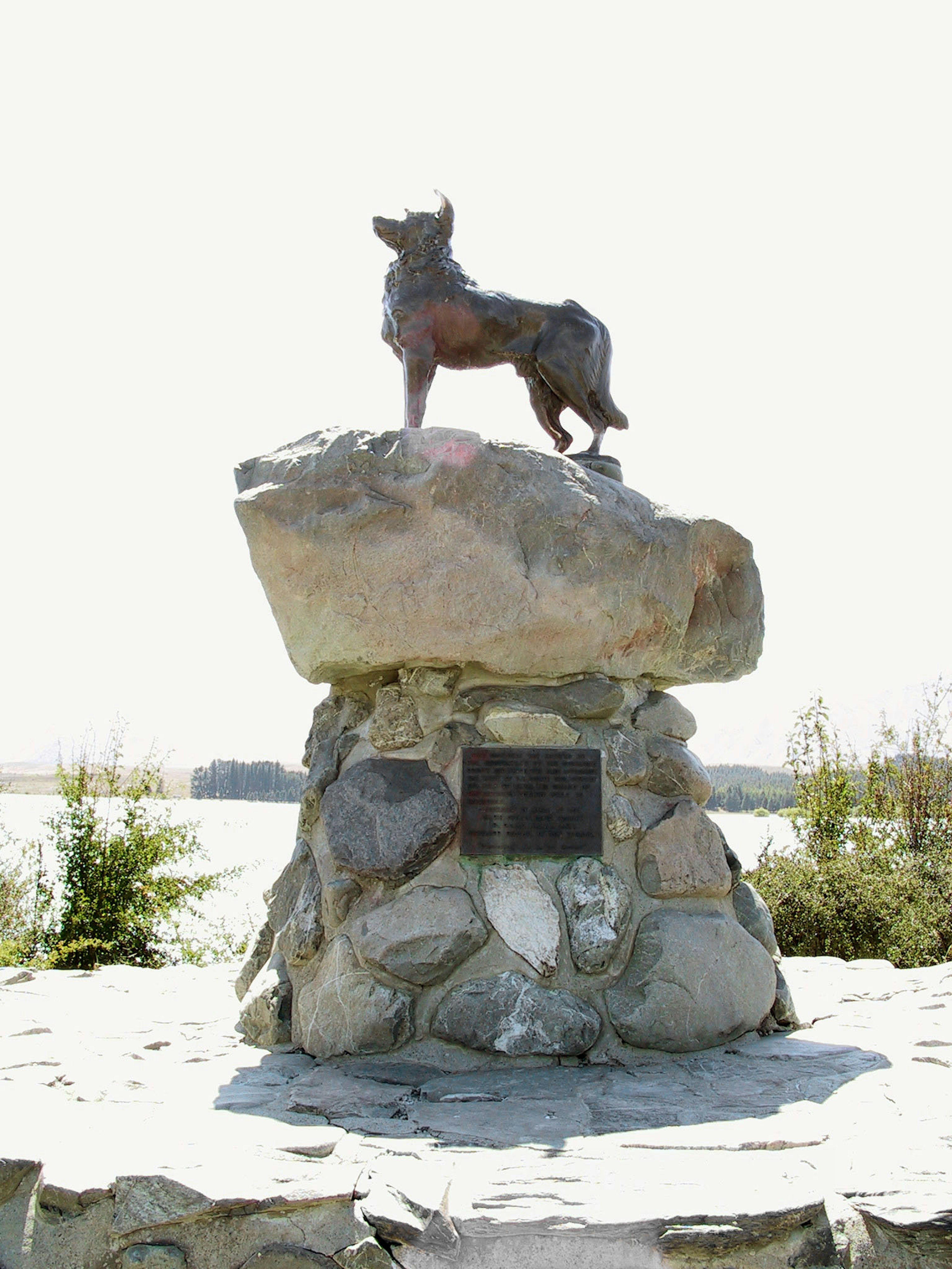 Une statue en bronze d'un chien se tenant sur une grande base en pierre