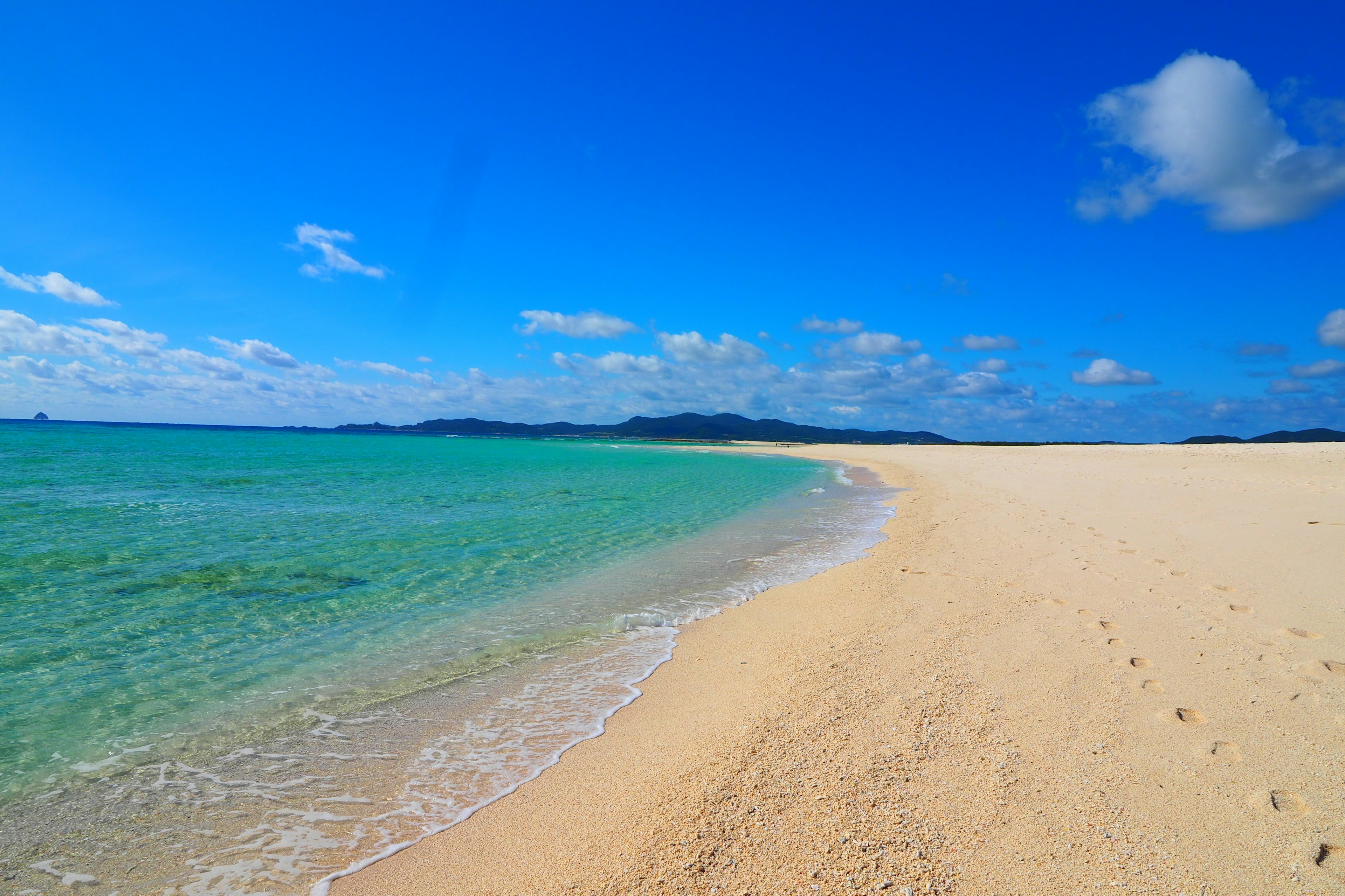 ทิวทัศน์ชายหาดที่มีท้องฟ้าสีฟ้าและน้ำทะเลสีเทอร์ควอยซ์