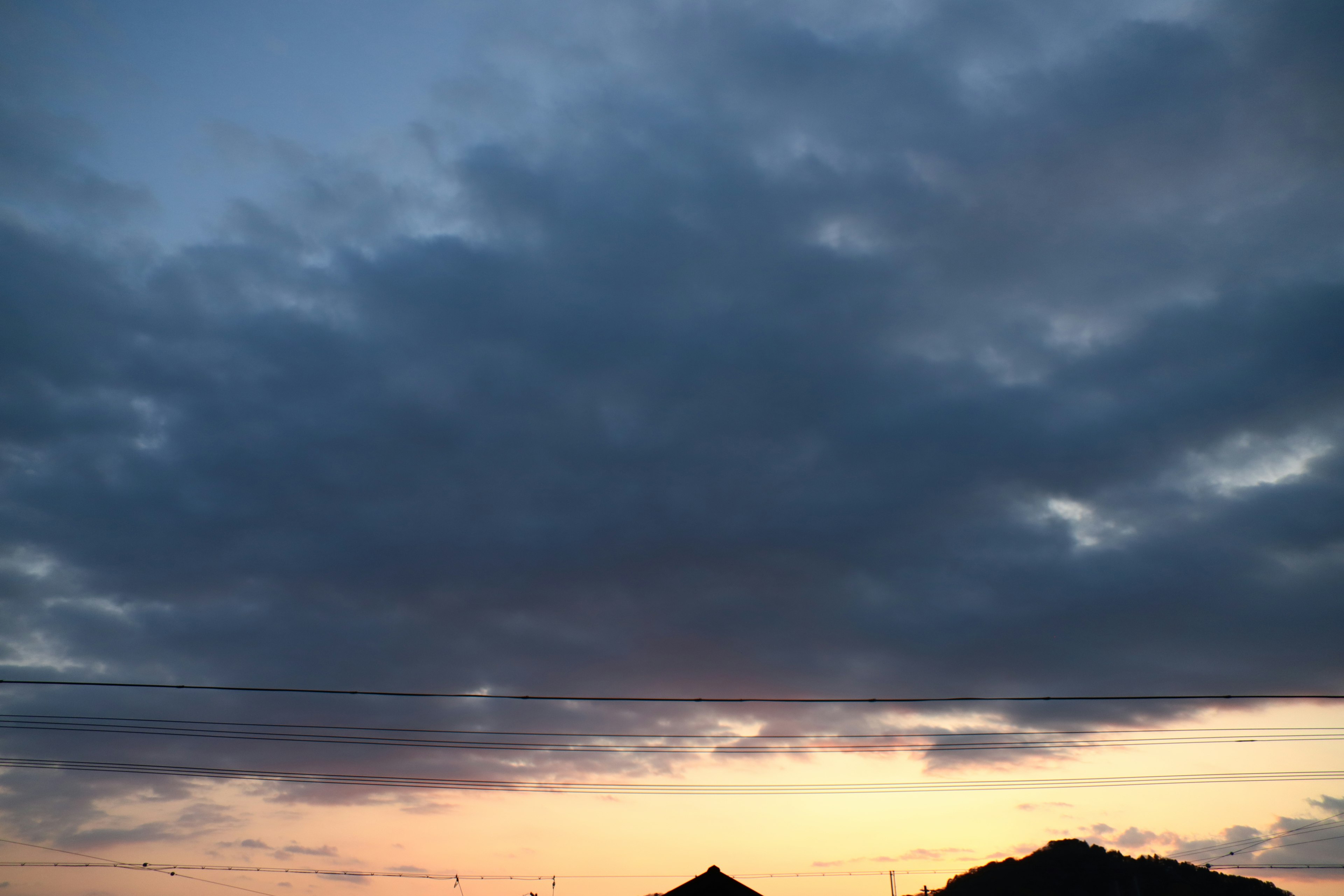 夕焼けの空に広がる雲のシルエットと暗い山の輪郭