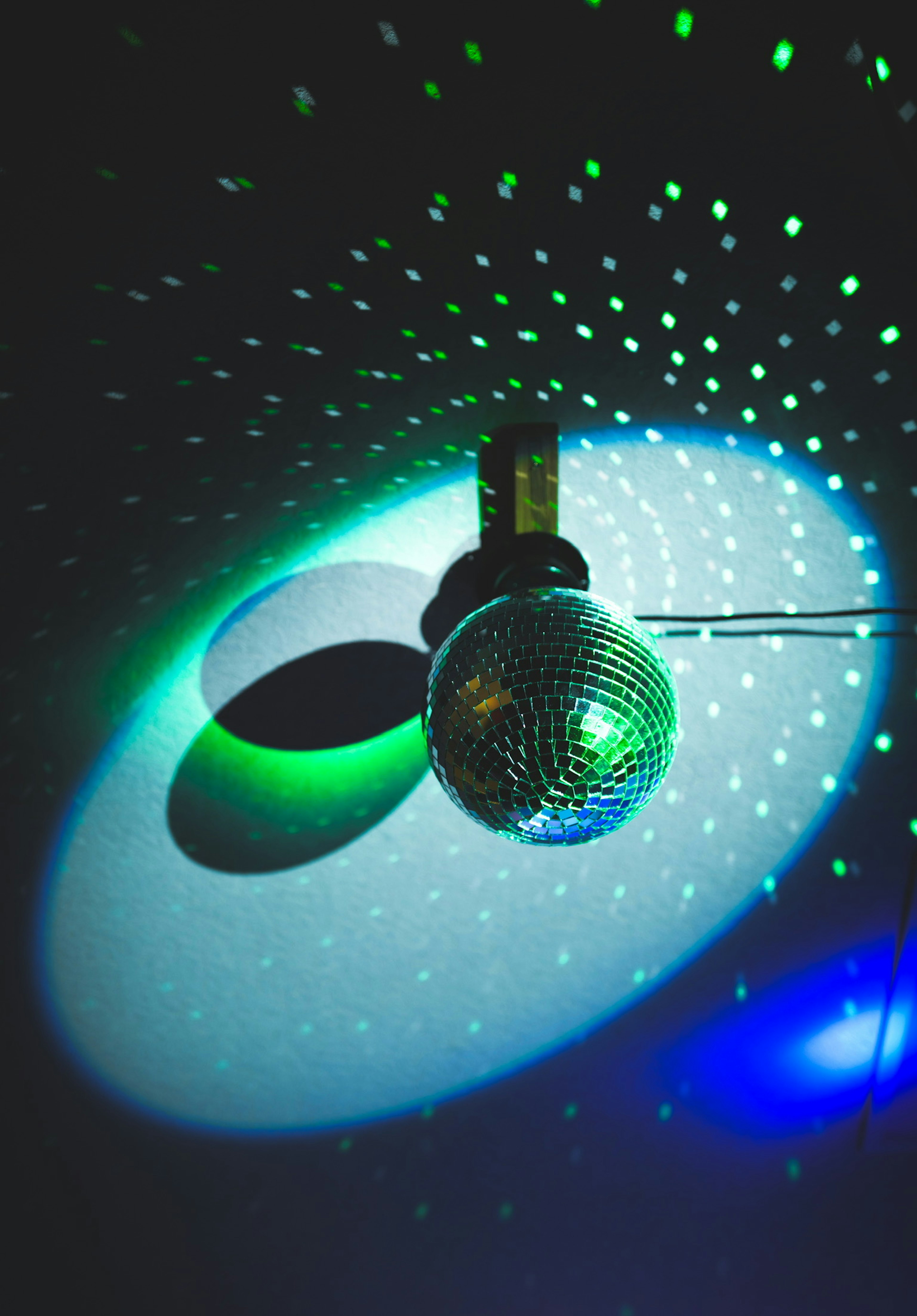 Disco ball reflecting light with colorful spotlights creating patterns on the ceiling