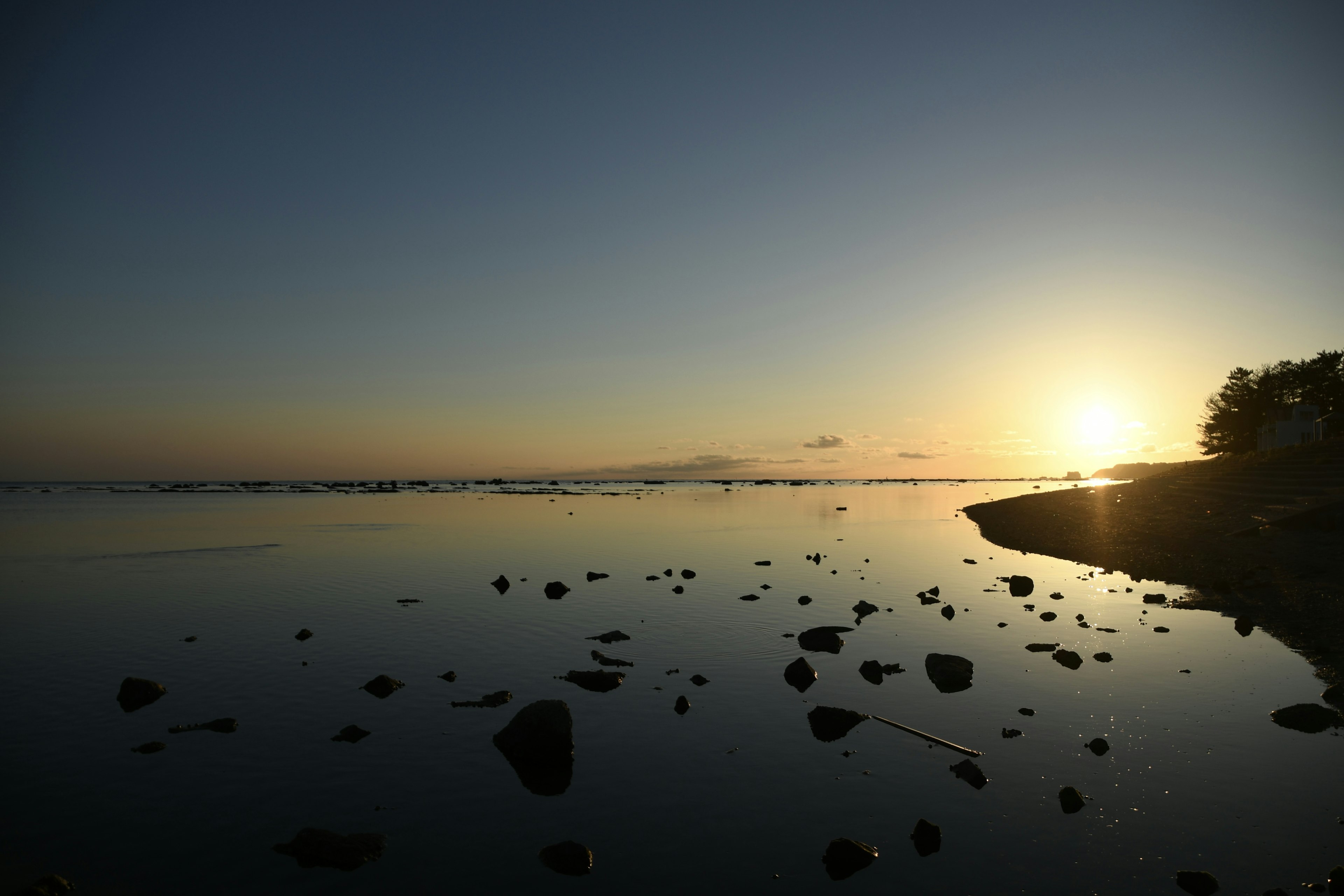 Paysage marin serein au coucher du soleil avec des rochers éparpillés le long du rivage