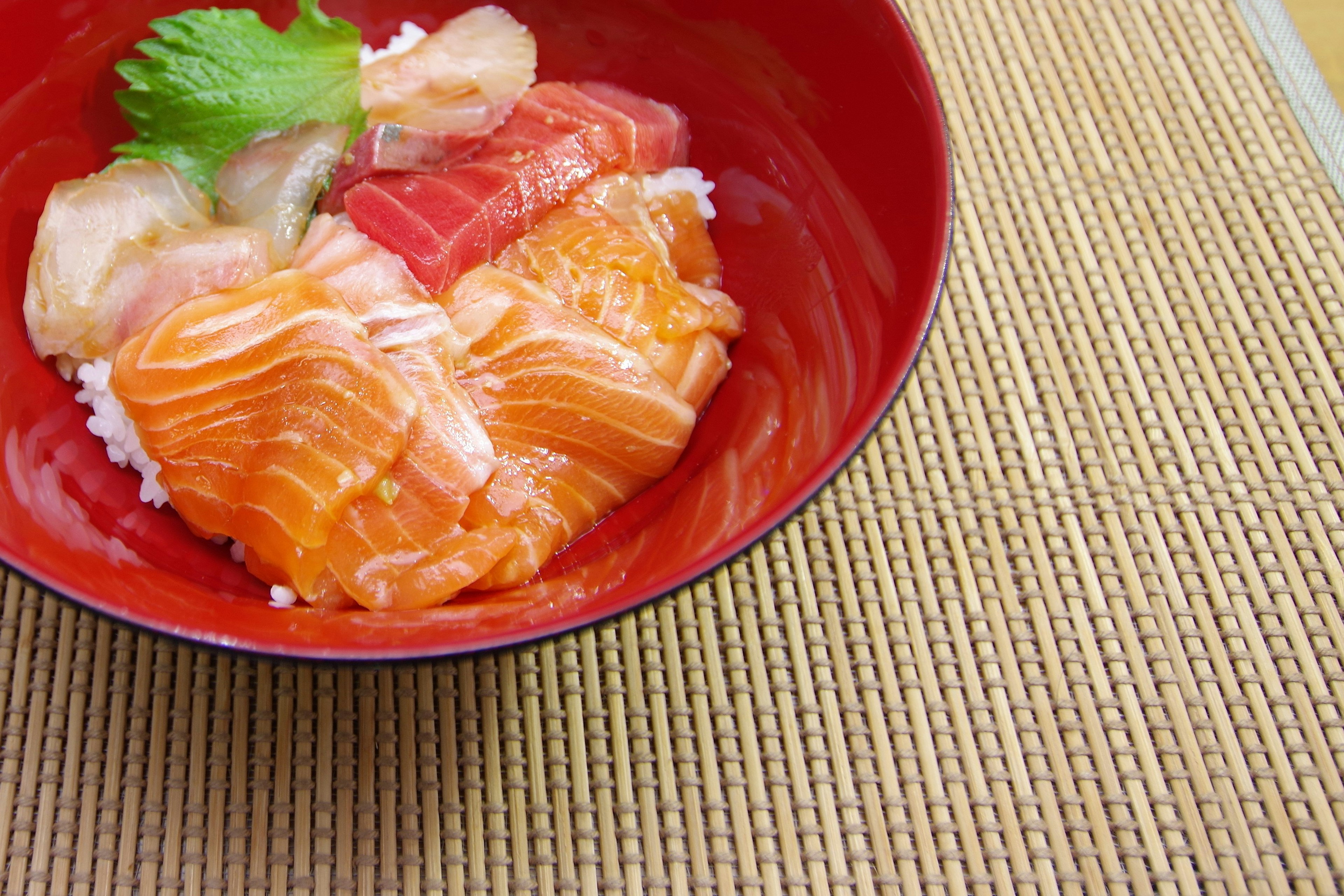 Mangkuk sashimi dengan salmon dan tuna dalam piring merah