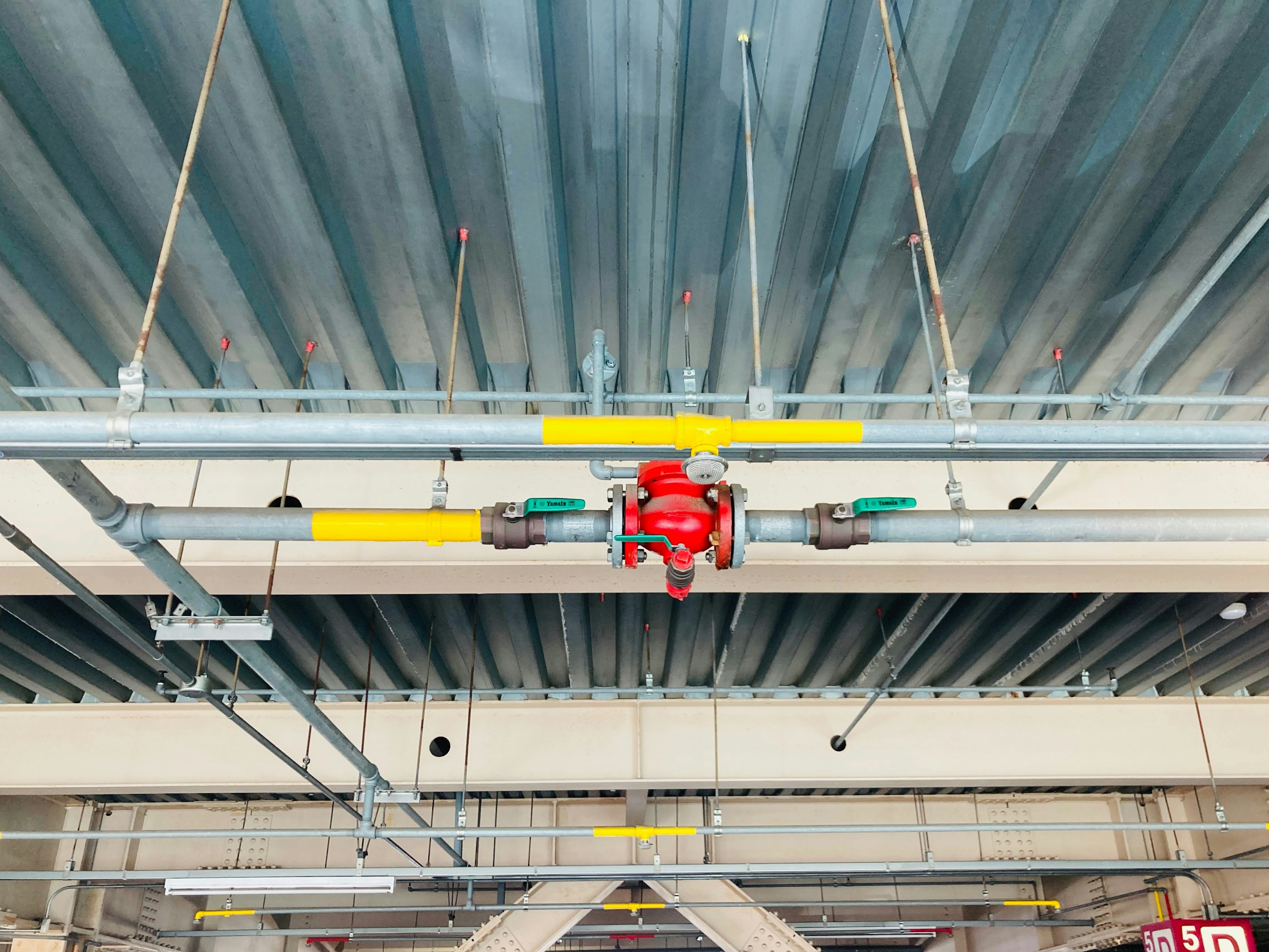 Mechanische Struktur mit einem roten Griff und grünen Komponenten, die an der Decke montiert sind