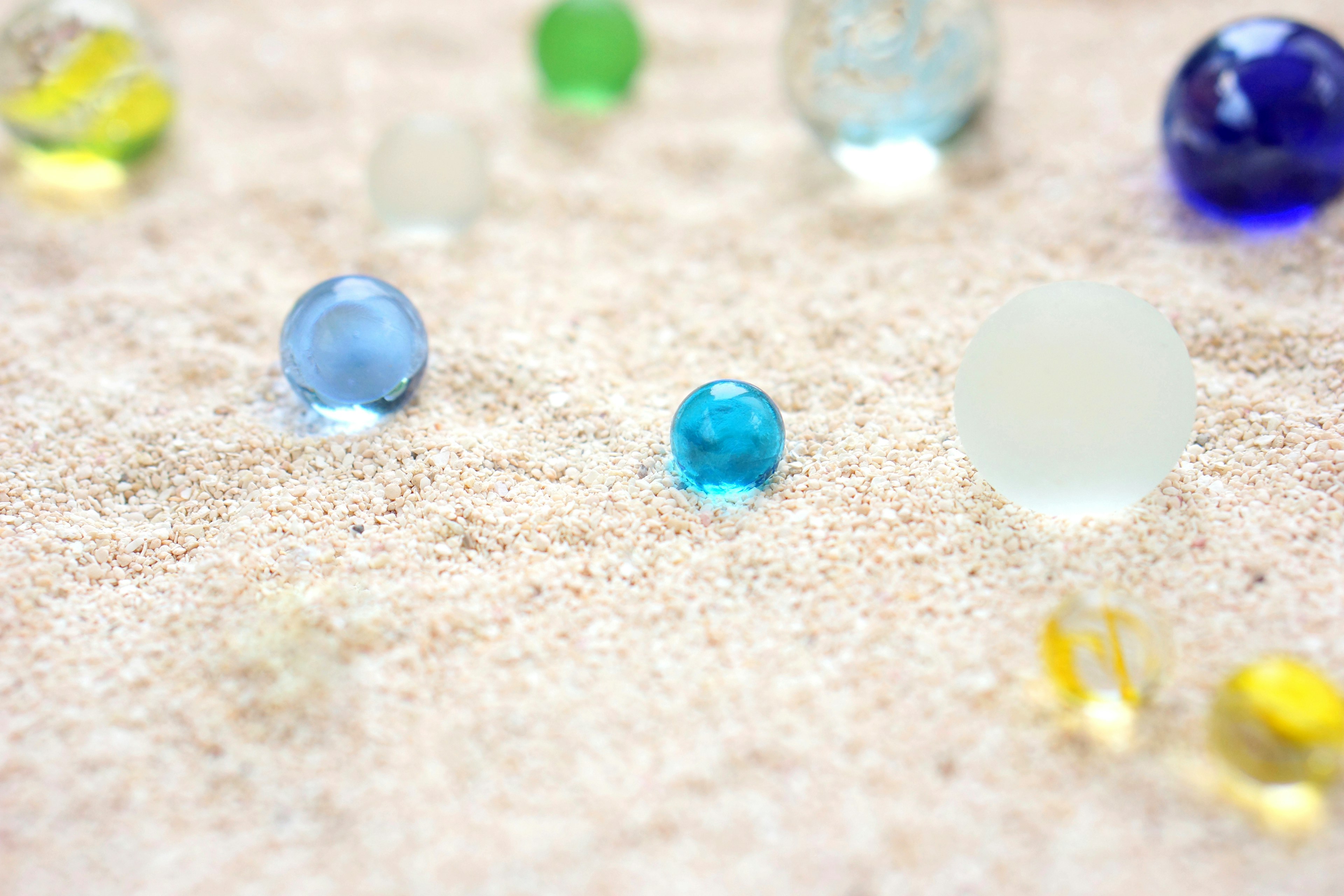 Billes en verre colorées éparpillées sur du sable