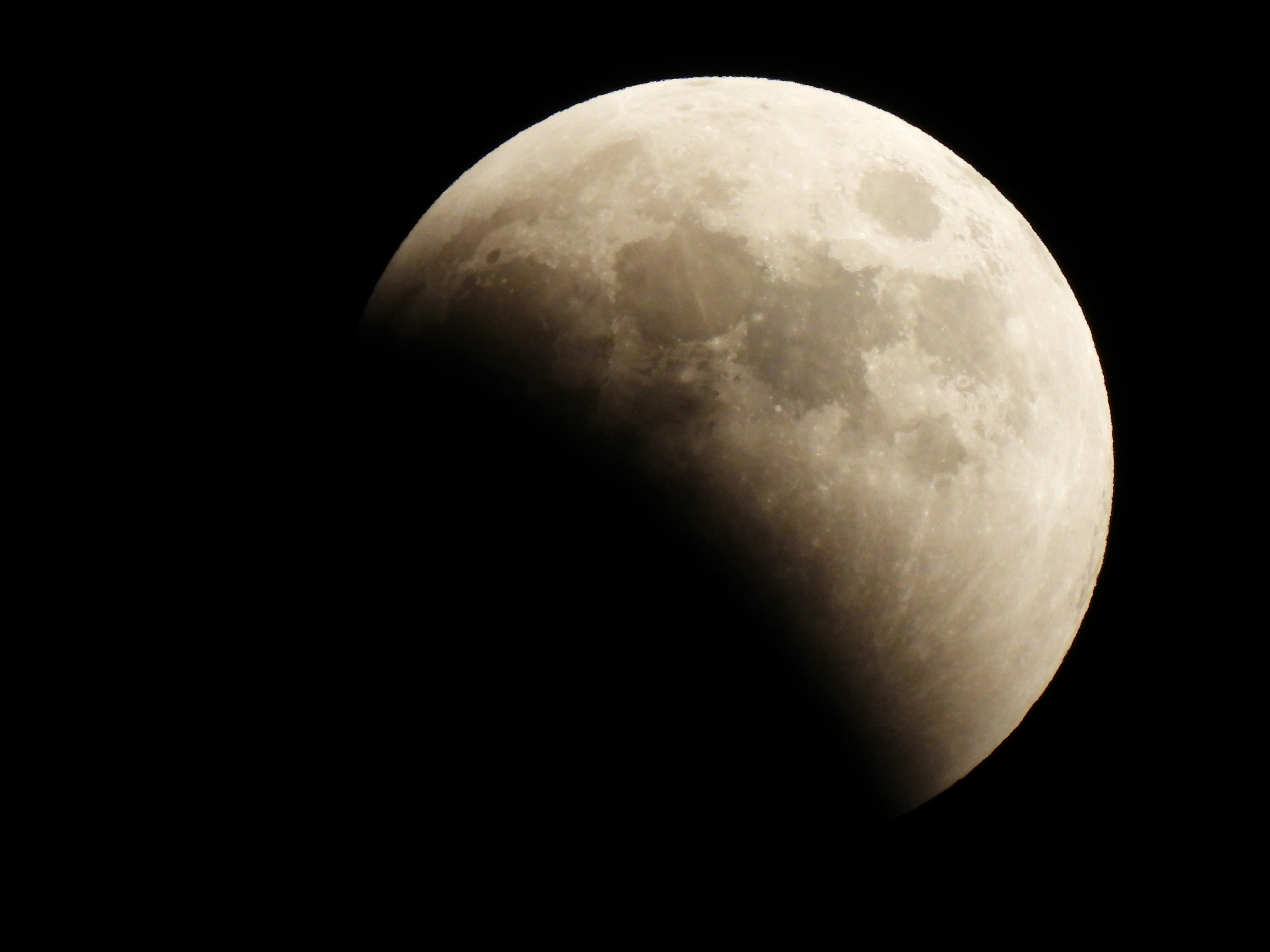 Eclipse lunar parcial con la luna iluminada contra un fondo oscuro