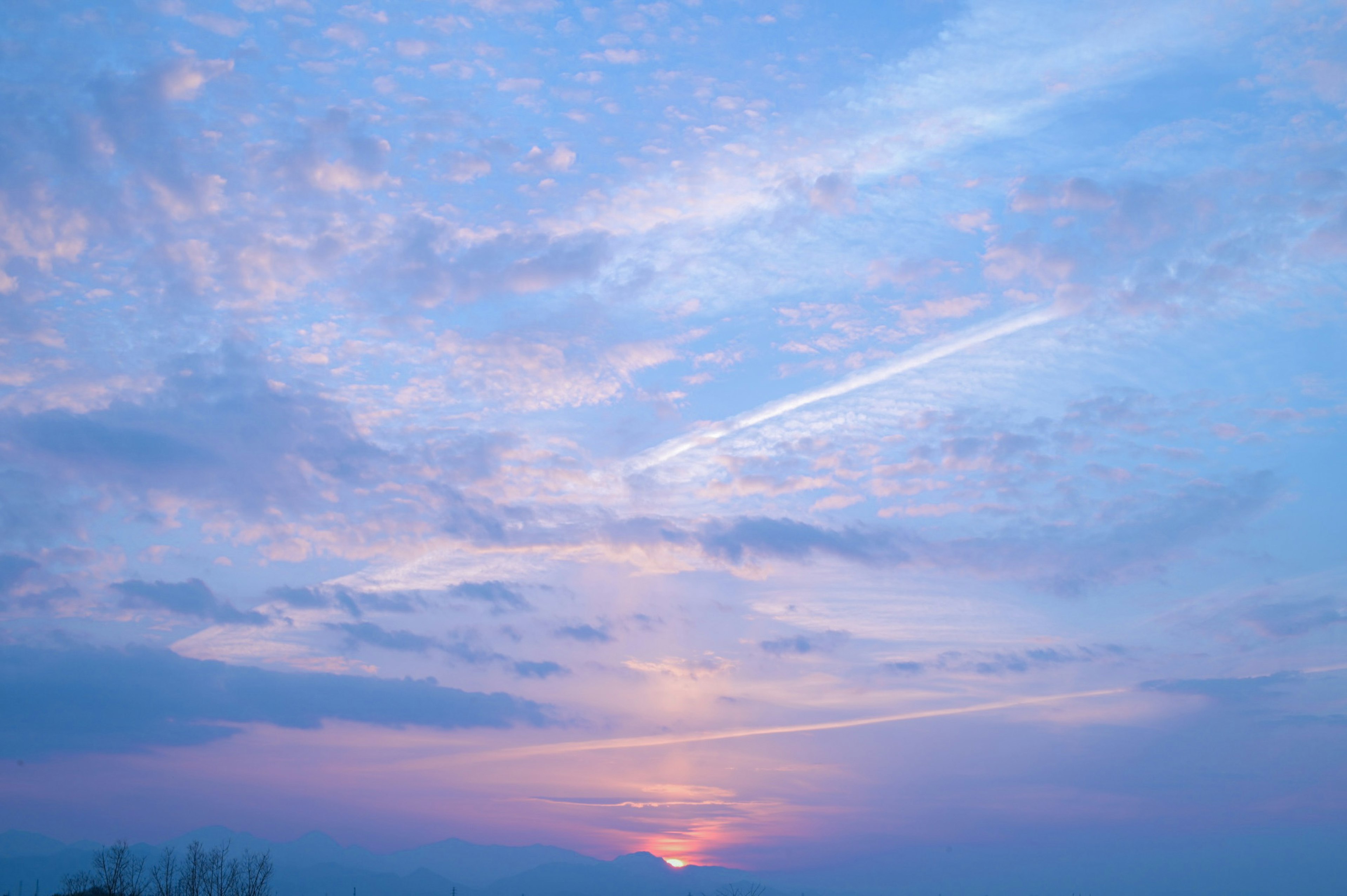美しい青空に浮かぶ雲と夕日が描かれた風景