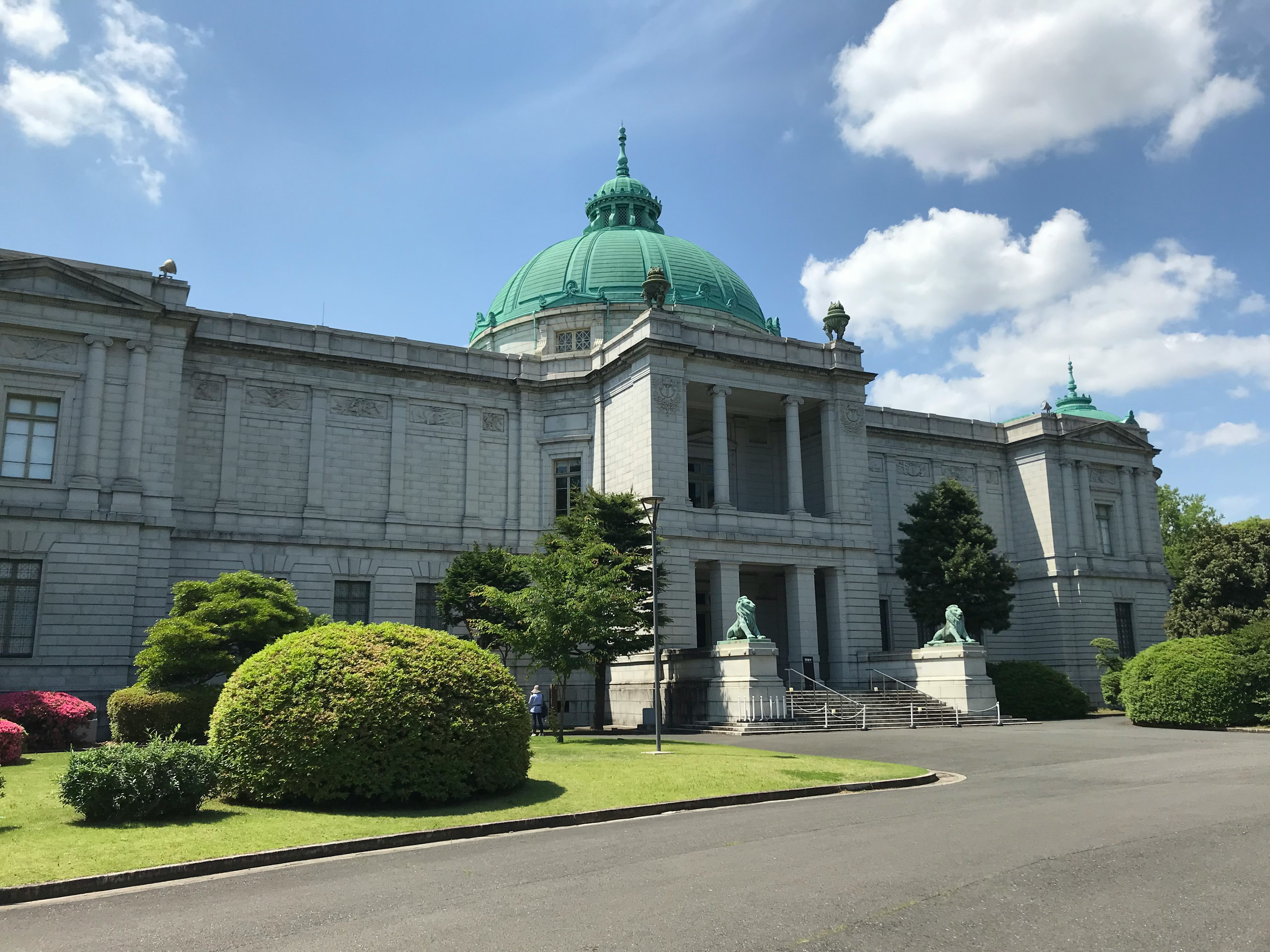 Edificio histórico con cúpula verde y jardín exuberante circundante