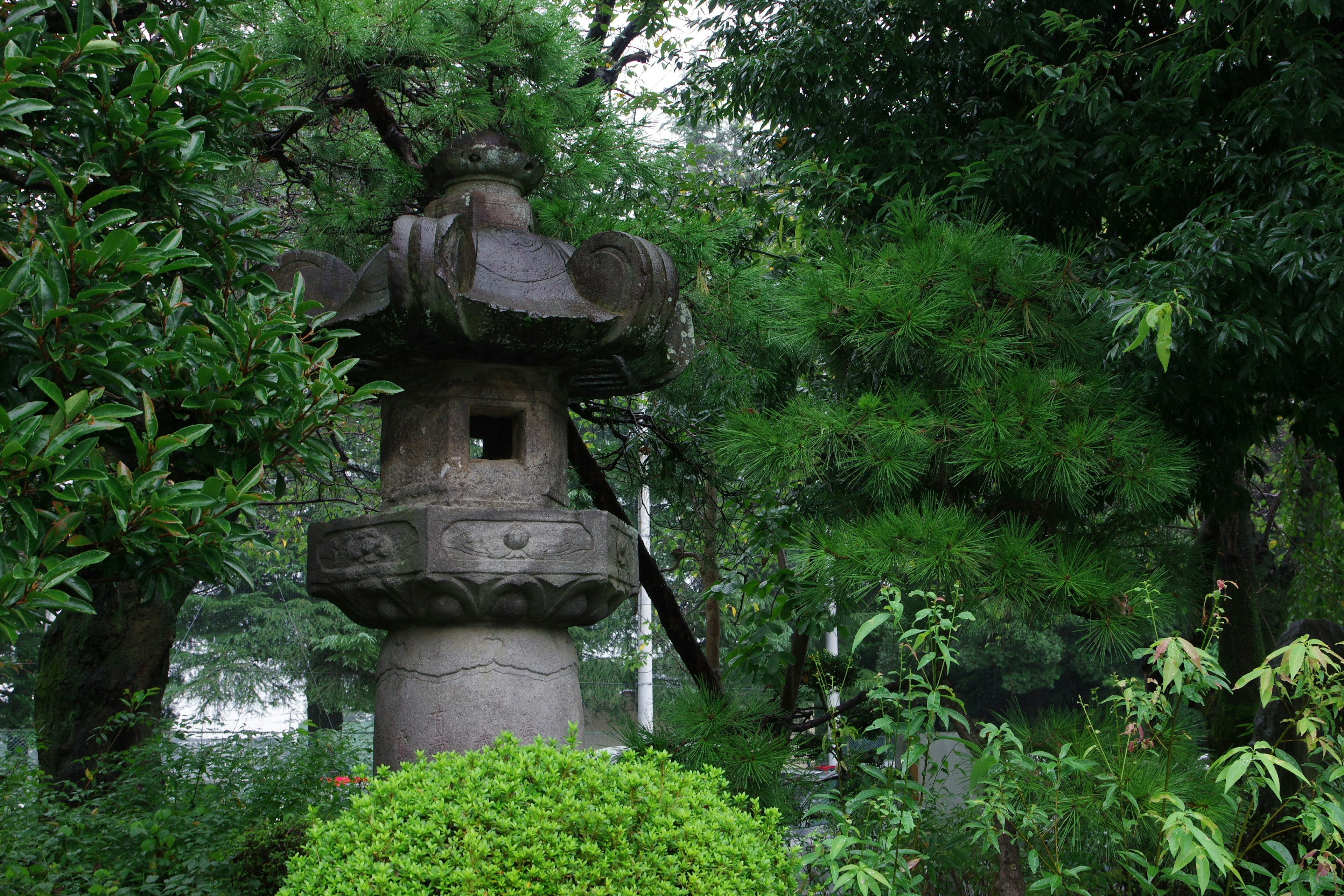 Lanterna di pietra in un giardino giapponese circondata da vegetazione lussureggiante