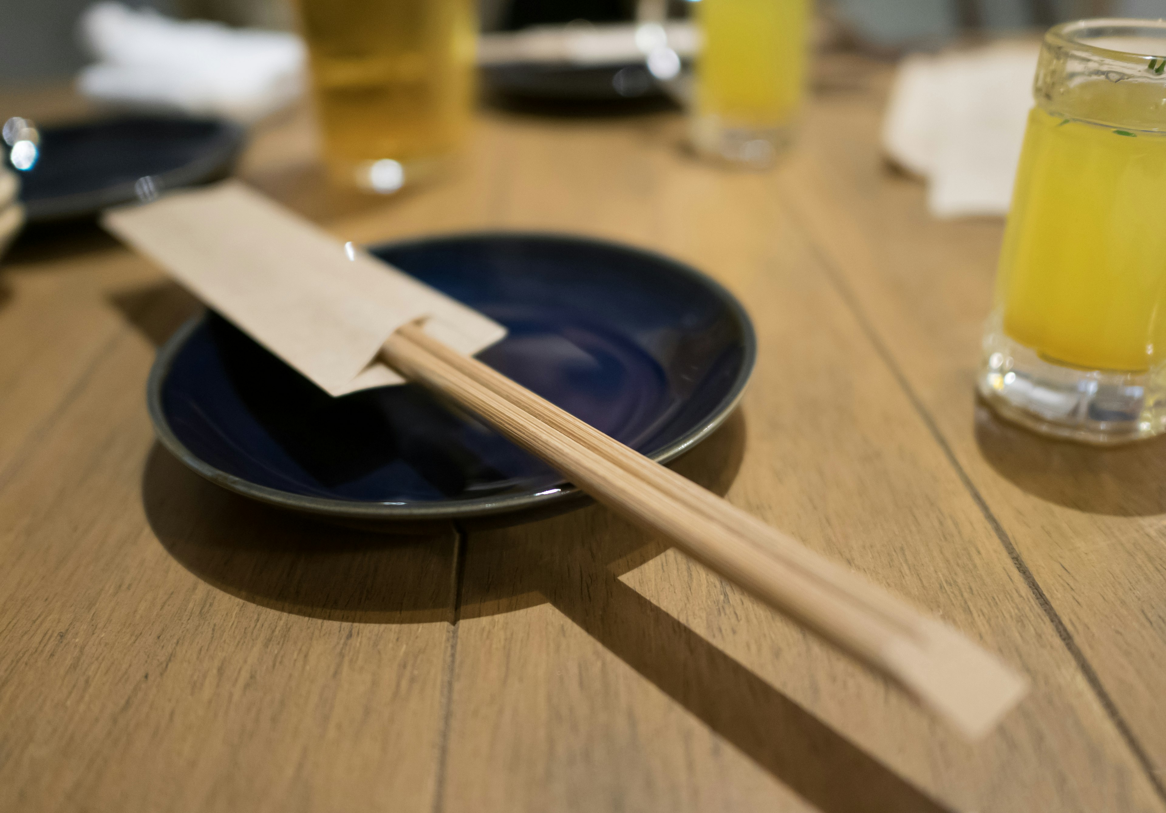 Wooden chopsticks resting on a blue plate with a menu