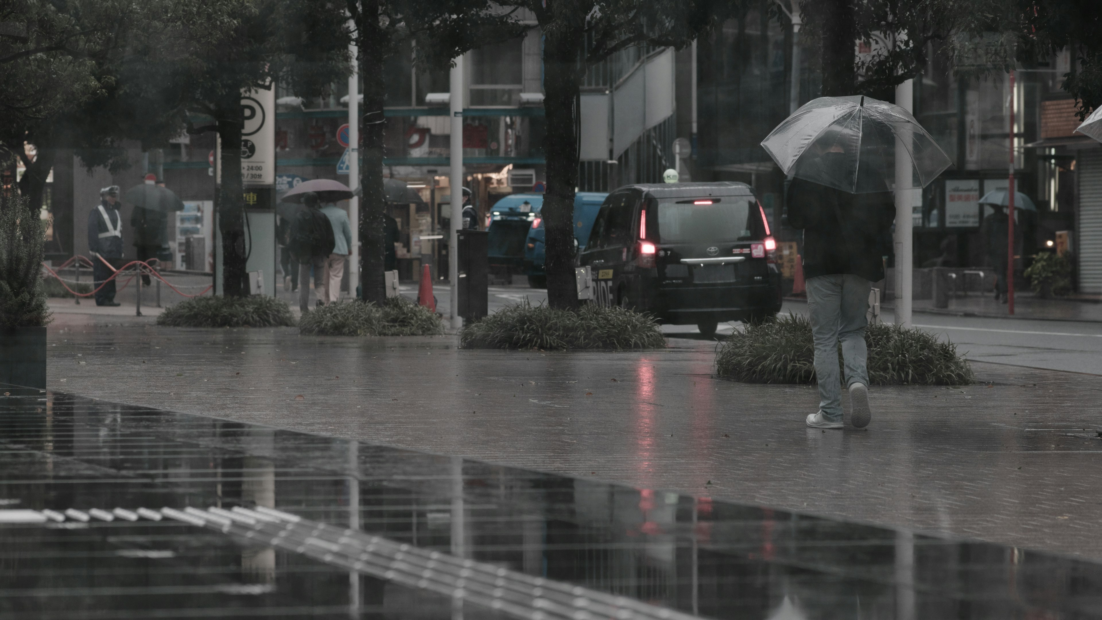 Stadtstraßenszene mit Menschen, die im Regen gehen und vorbeifahrenden Autos