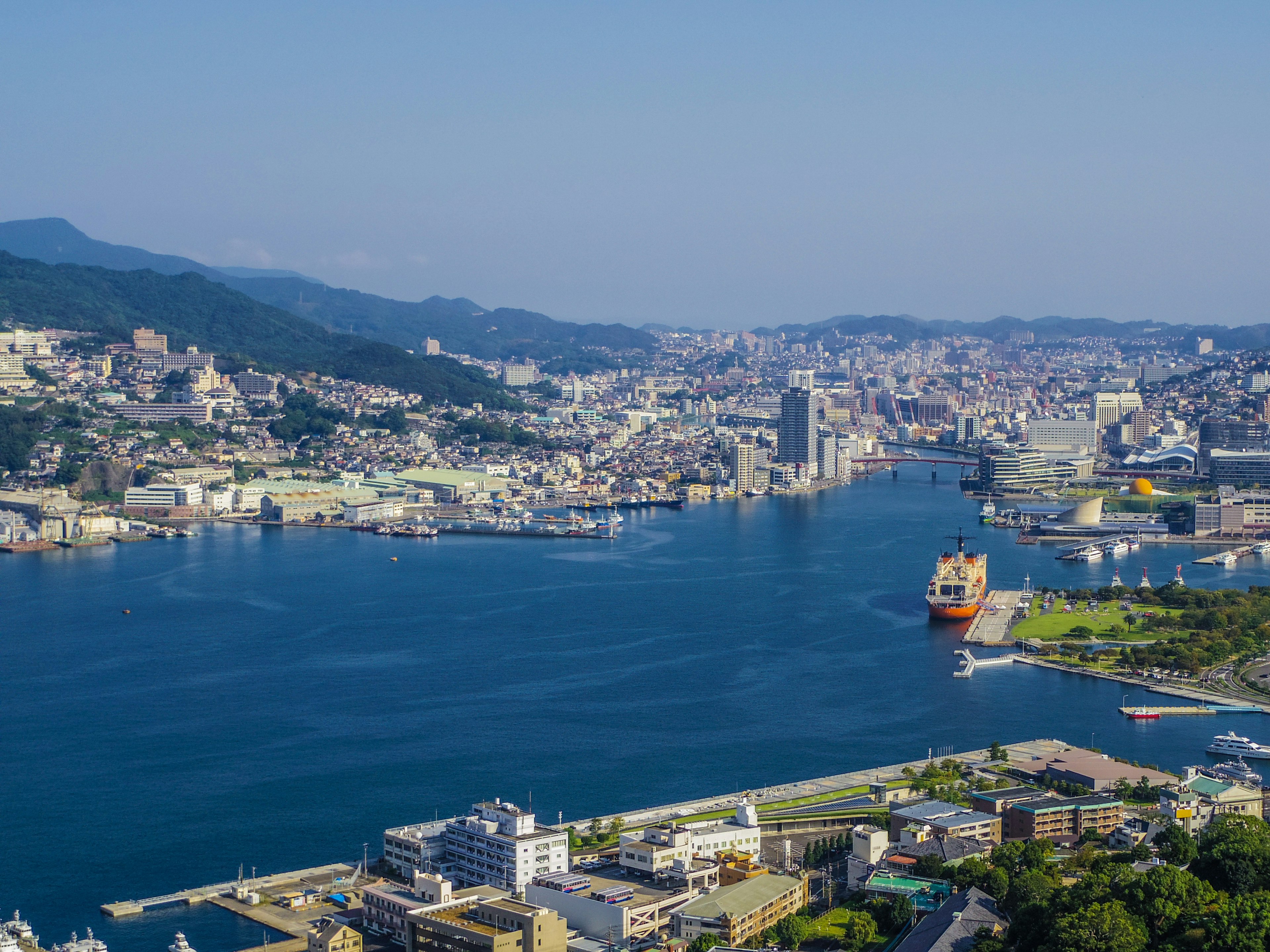 ทิวทัศน์พานอรามาของท่าเรือนางาซากิกับภูเขาในพื้นหลัง