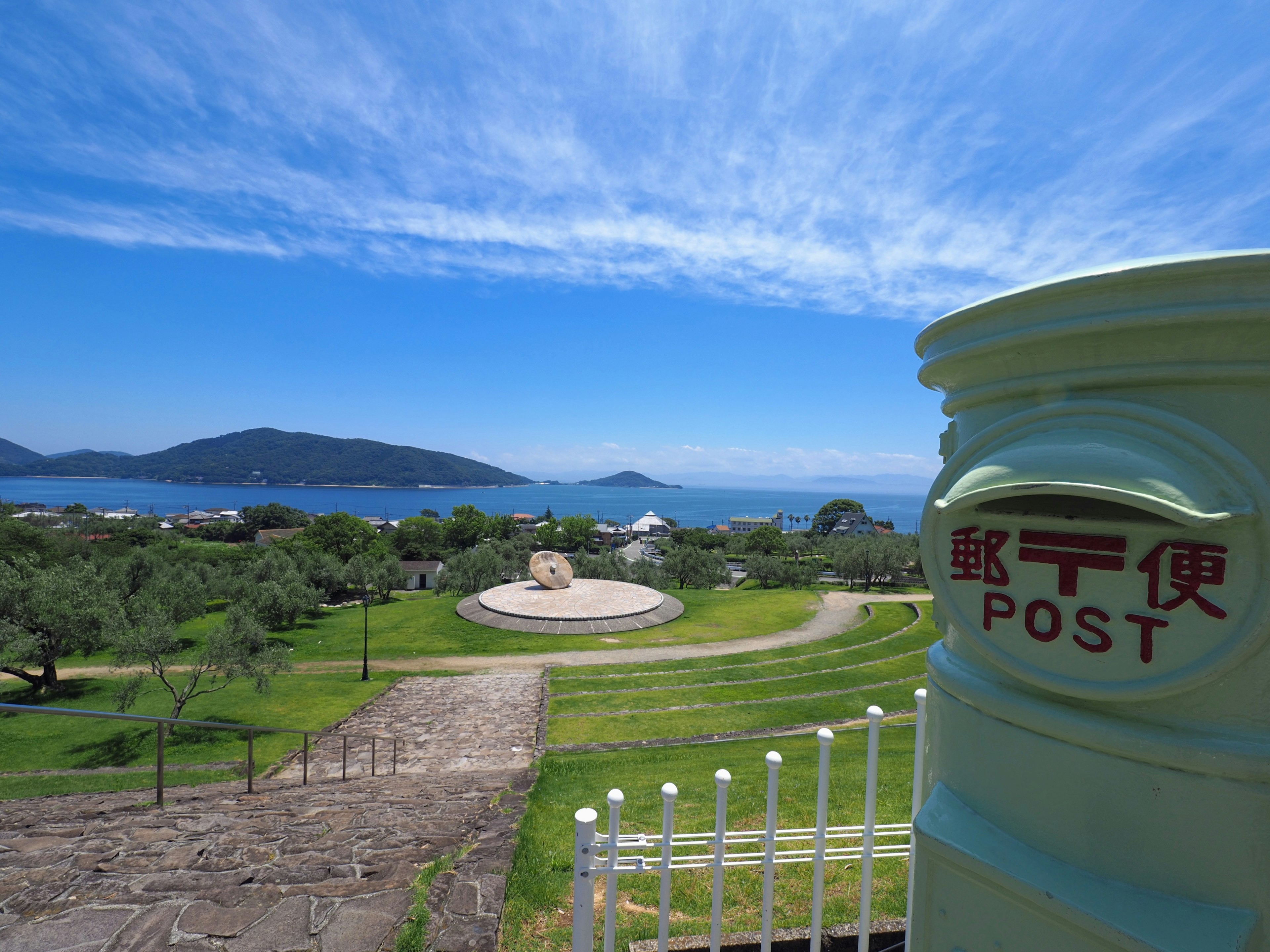 Une boîte aux lettres avec un parc pittoresque et une vue sur l'océan sous un ciel bleu clair