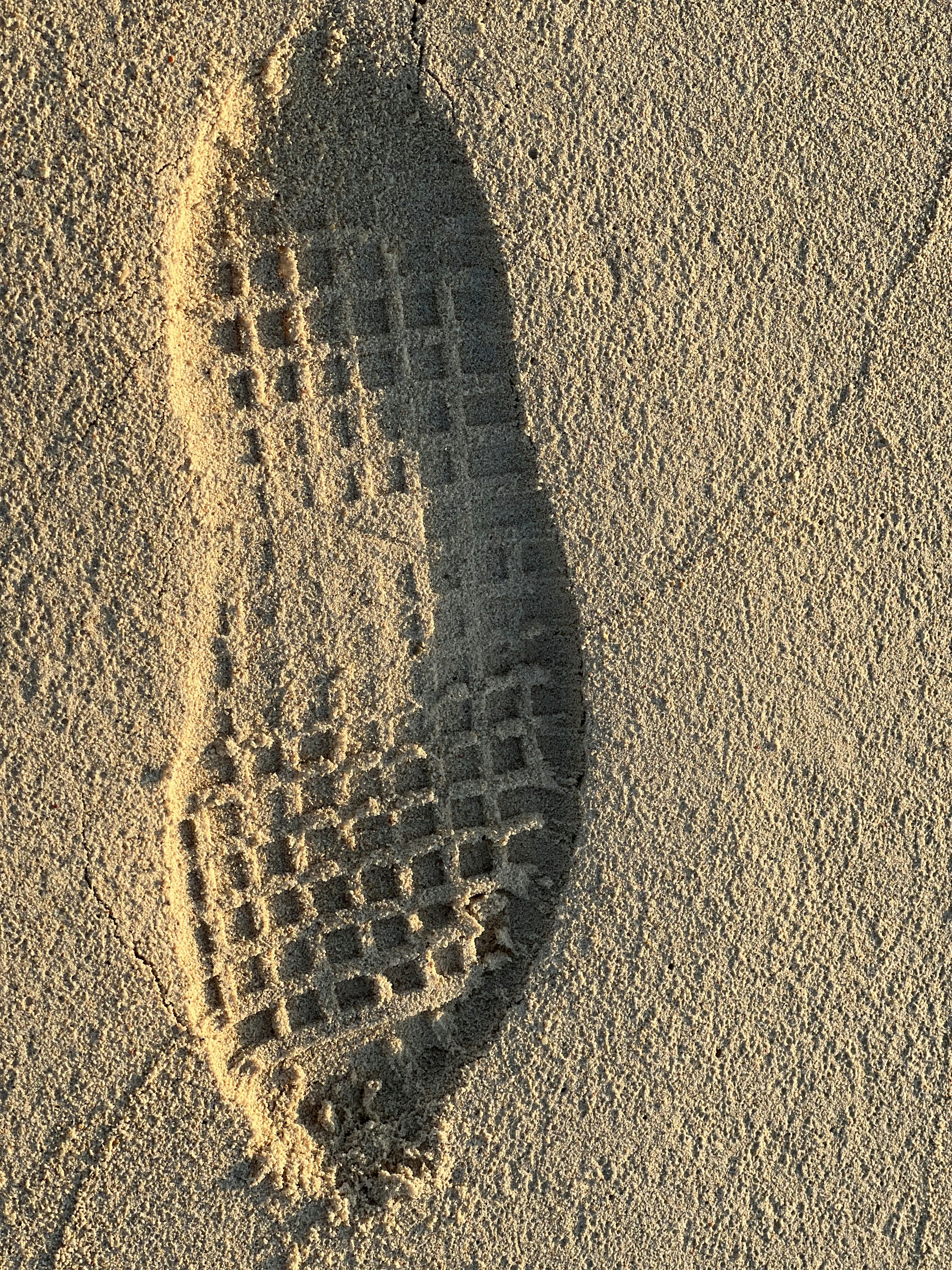 Empreinte de chaussure détaillée dans le sable