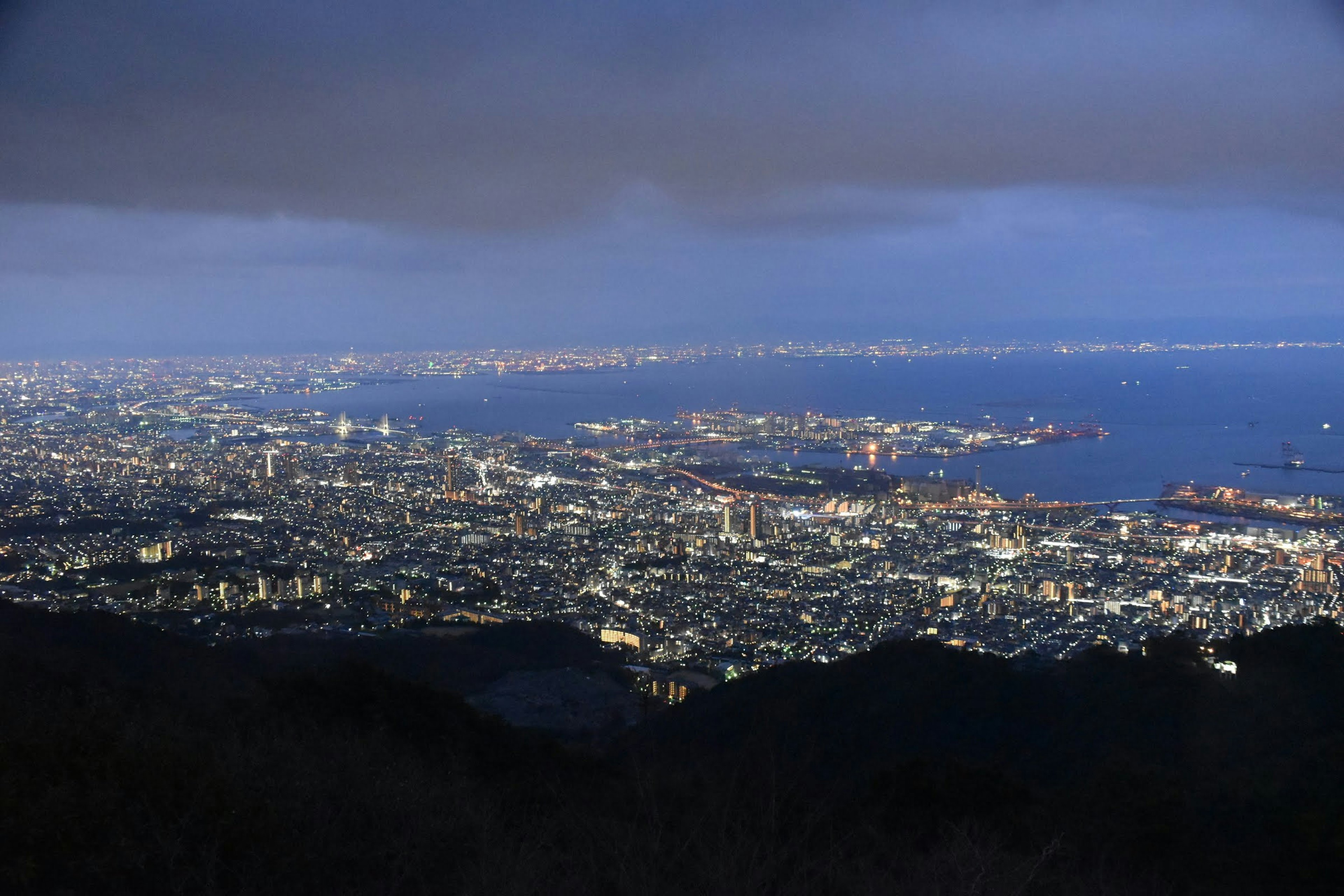 Vista panorámica de una ciudad de noche con mar y luces de edificios