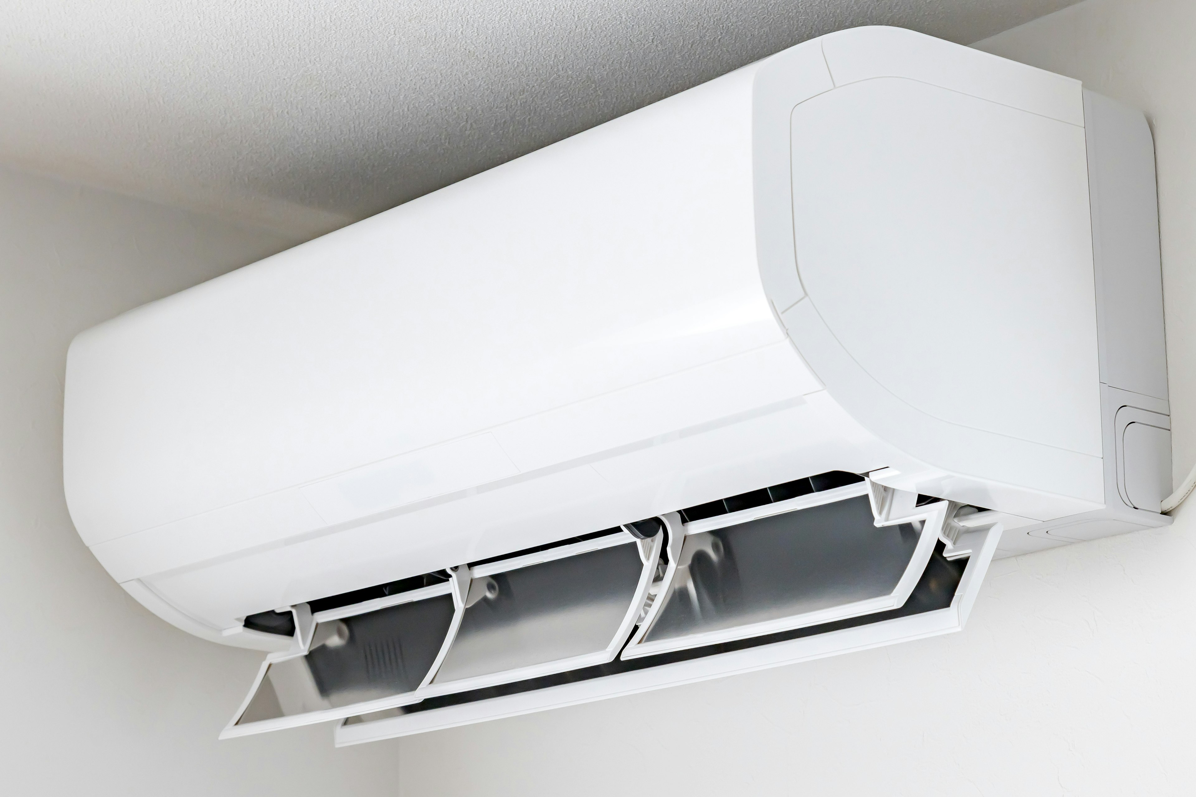 Wall-mounted air conditioner in white design with open vents