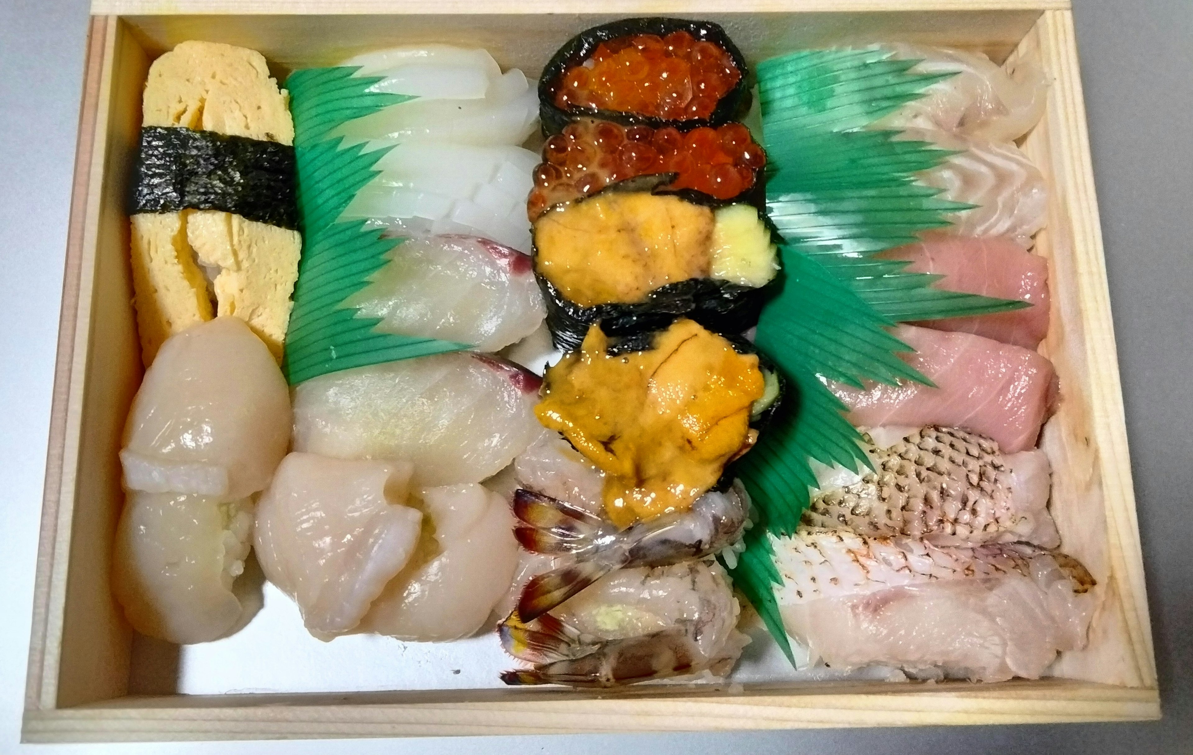 A wooden box filled with an assortment of fresh sushi