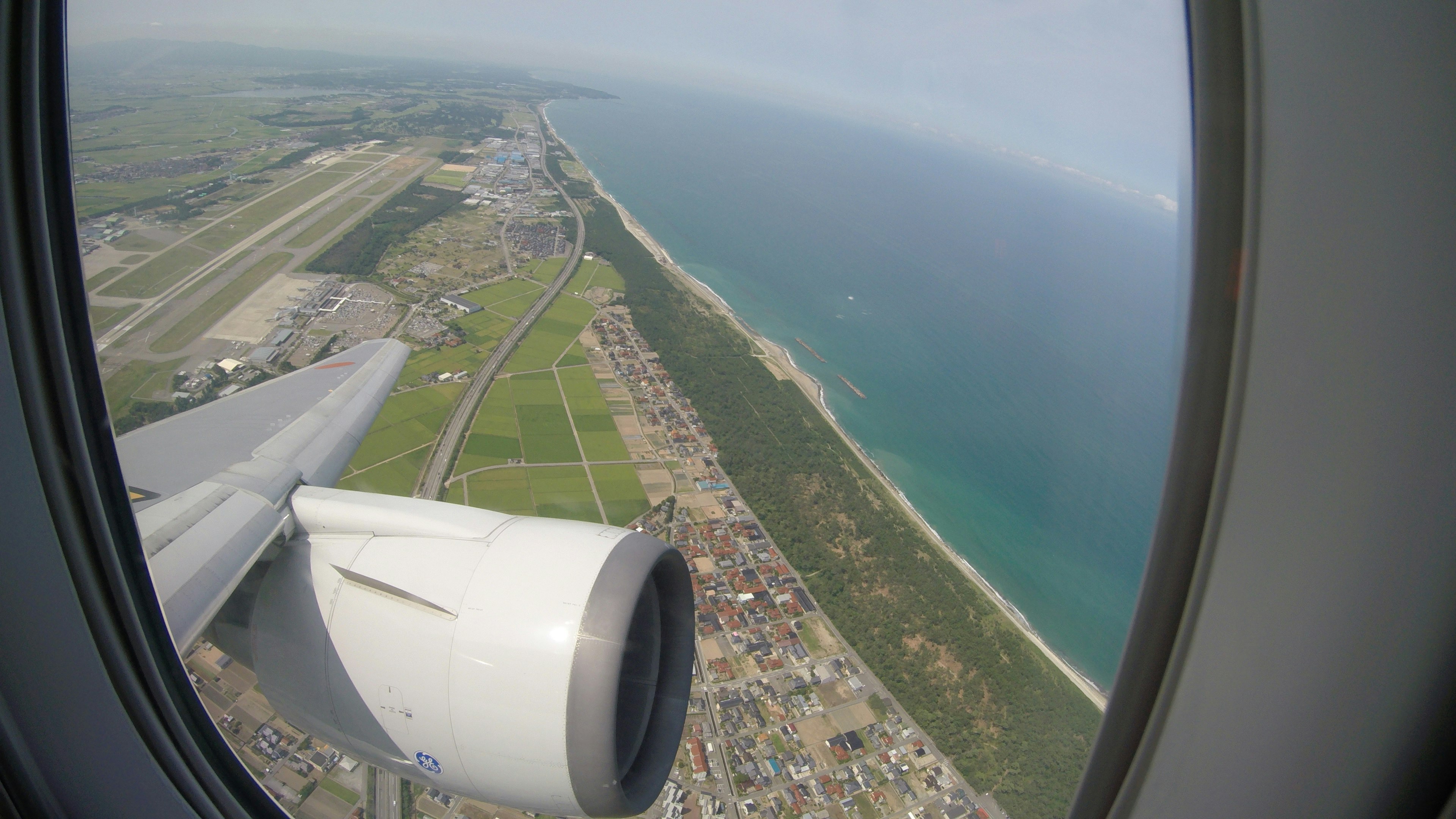 Blick aus dem Flugzeugfenster auf die Küste und den Flughafen