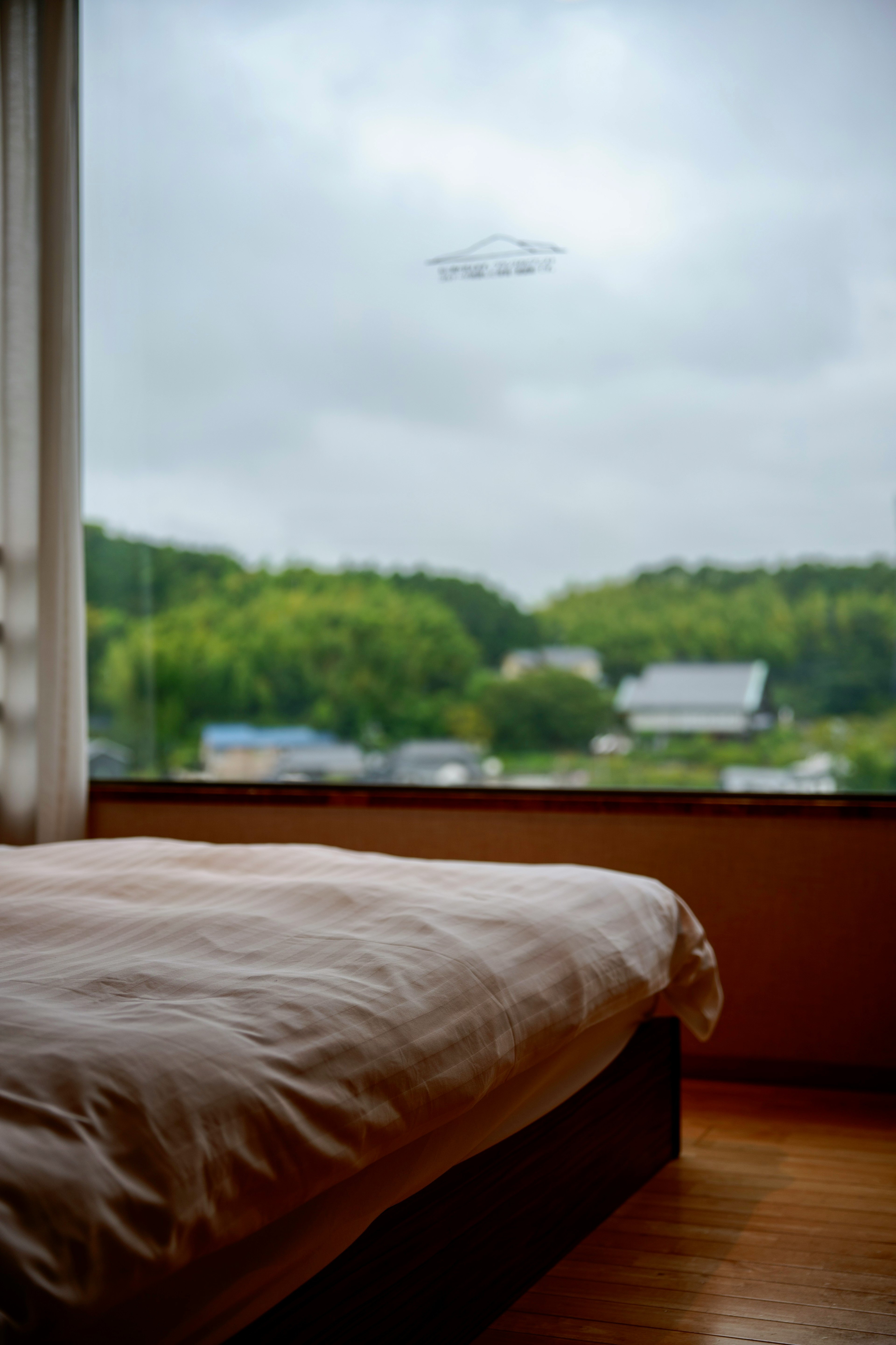 Interior scene of a bedroom with a view of green landscape outside the window