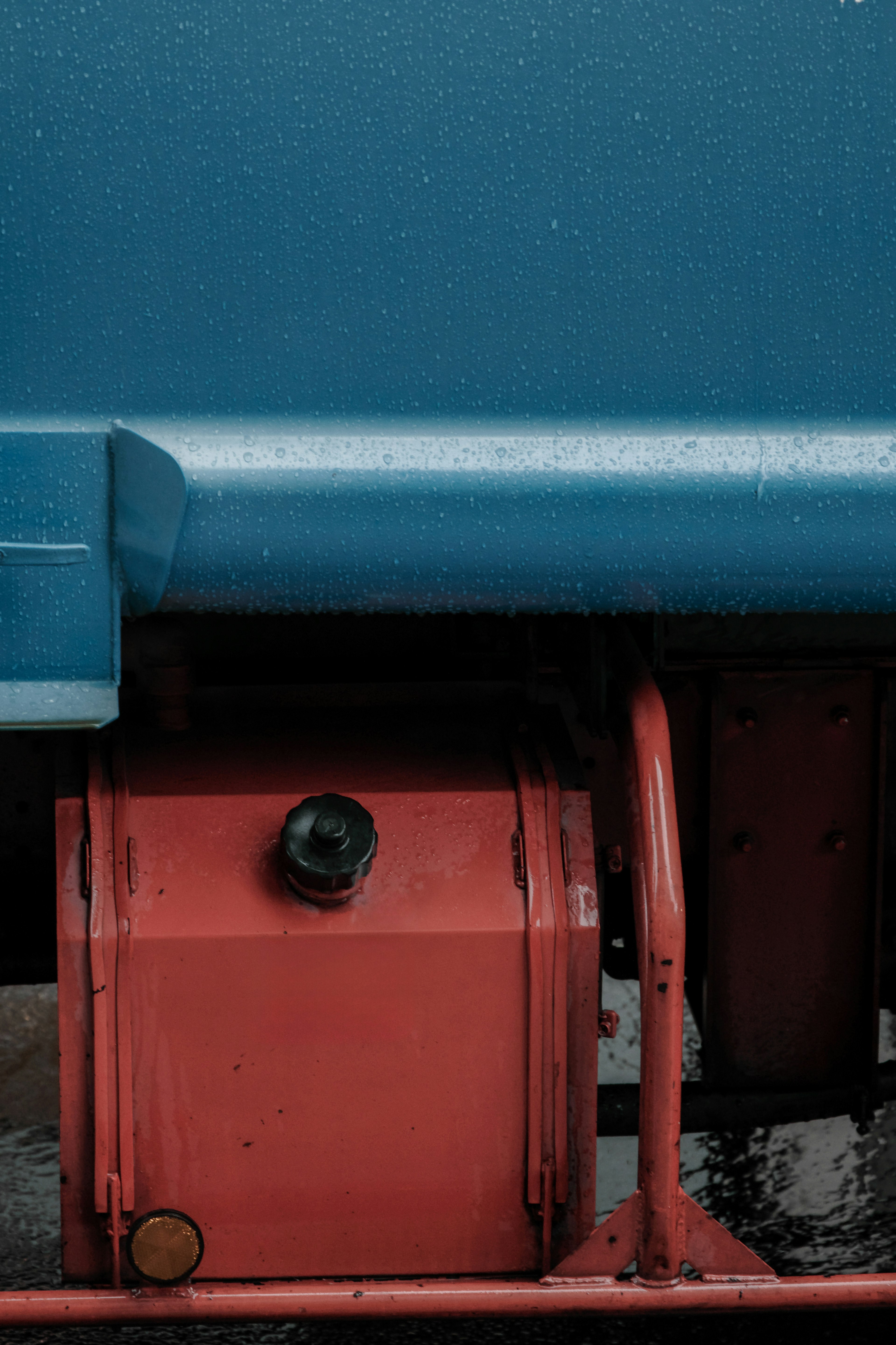 Roter Tank unter einem blauen Fahrzeug mit Regentropfen