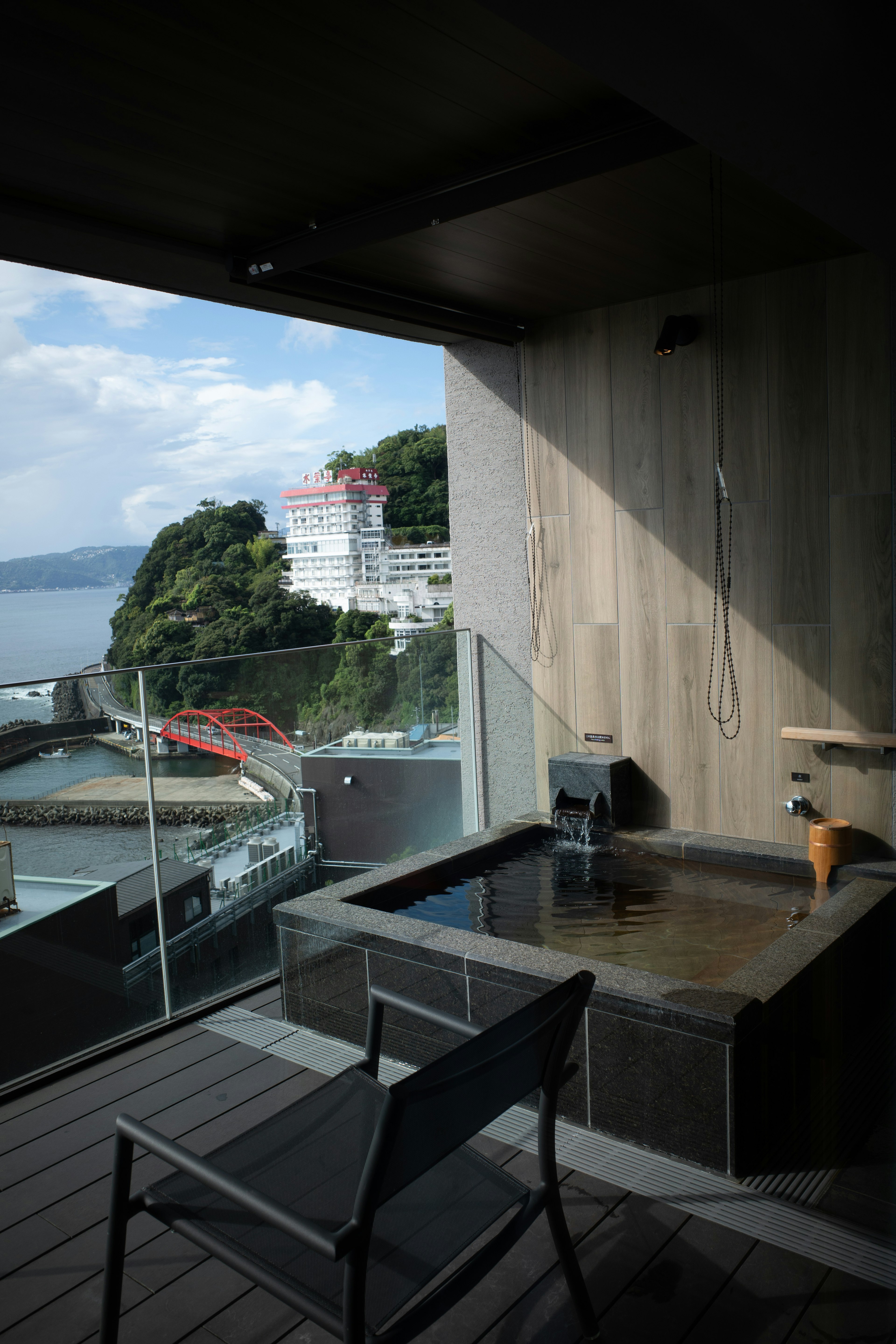 Vasca idromassaggio all'aperto su un balcone con vista sul mare e una sedia