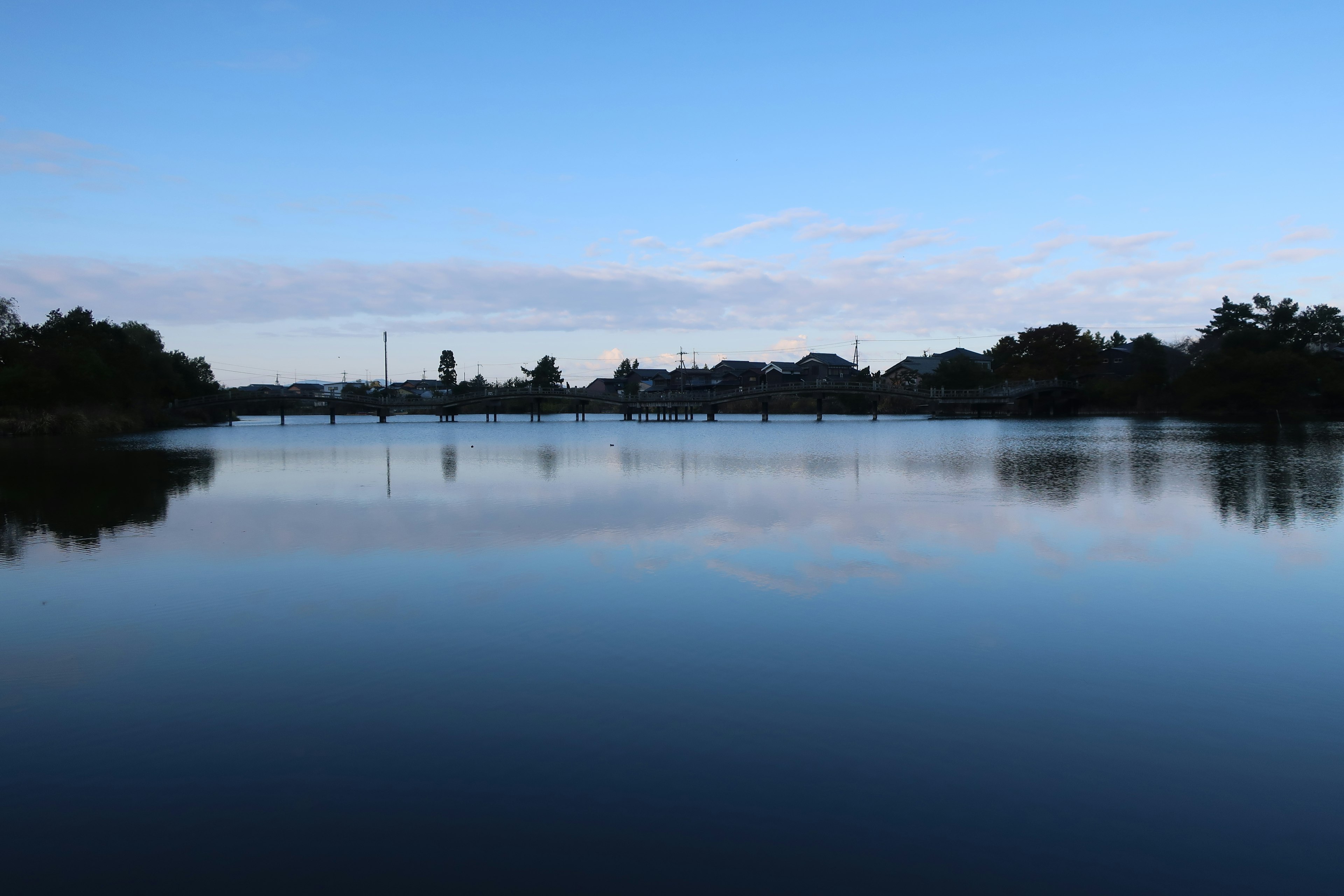 Danau tenang yang memantulkan langit biru dan awan