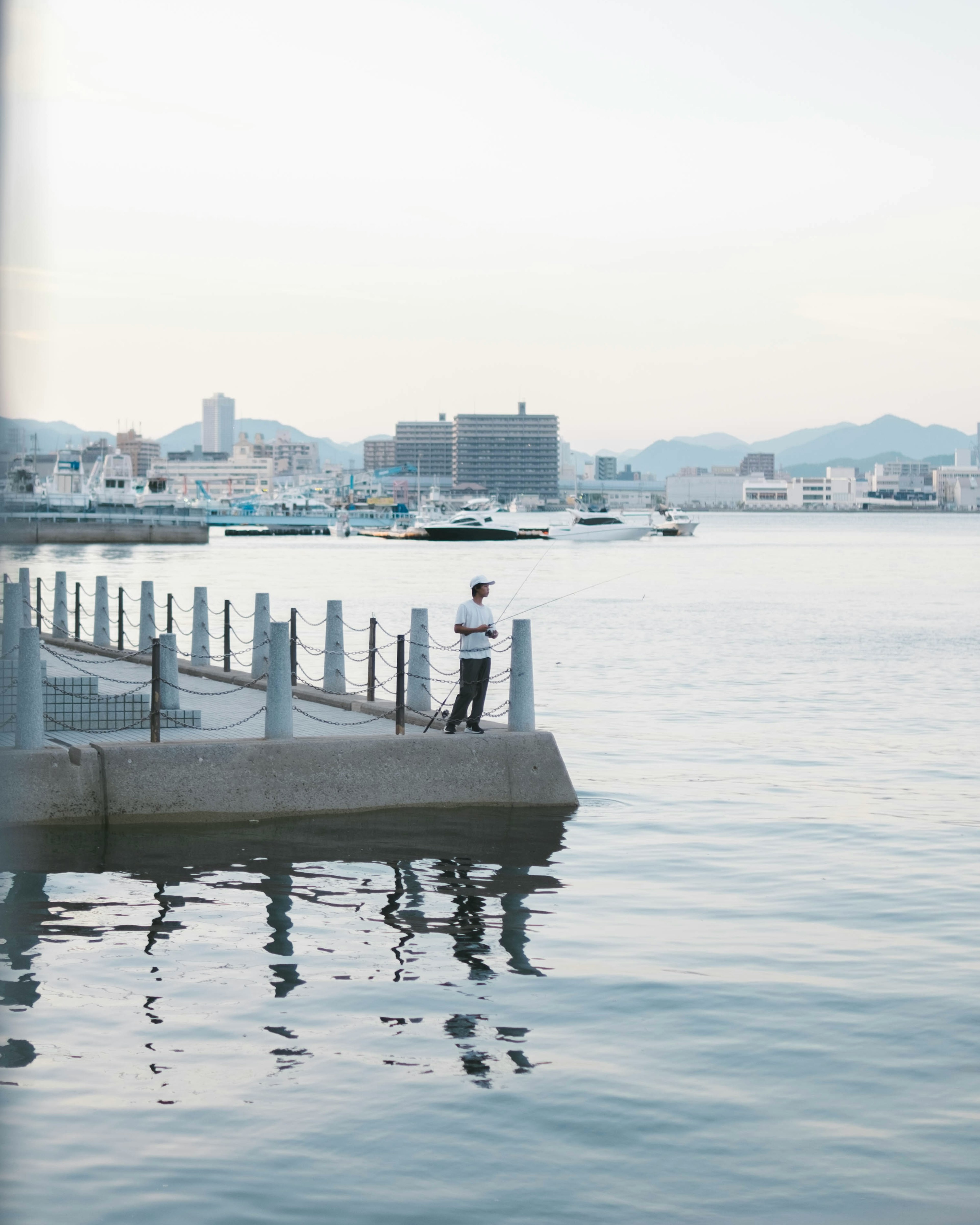 Eine Person steht auf einem ruhigen Pier mit ruhigem Wasser im Hintergrund