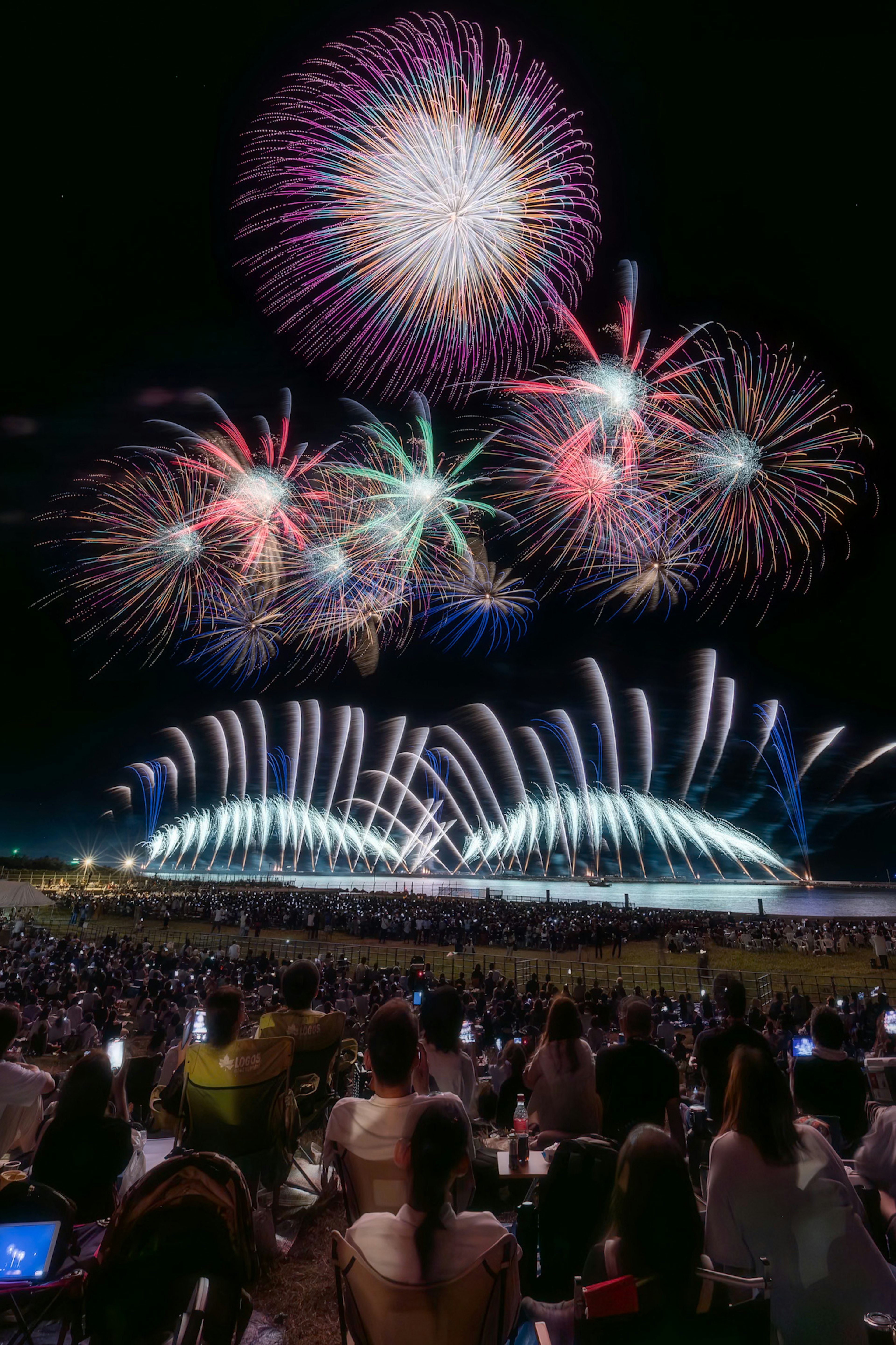 夜空を彩る花火が打ち上げられ観客が見守るシーン