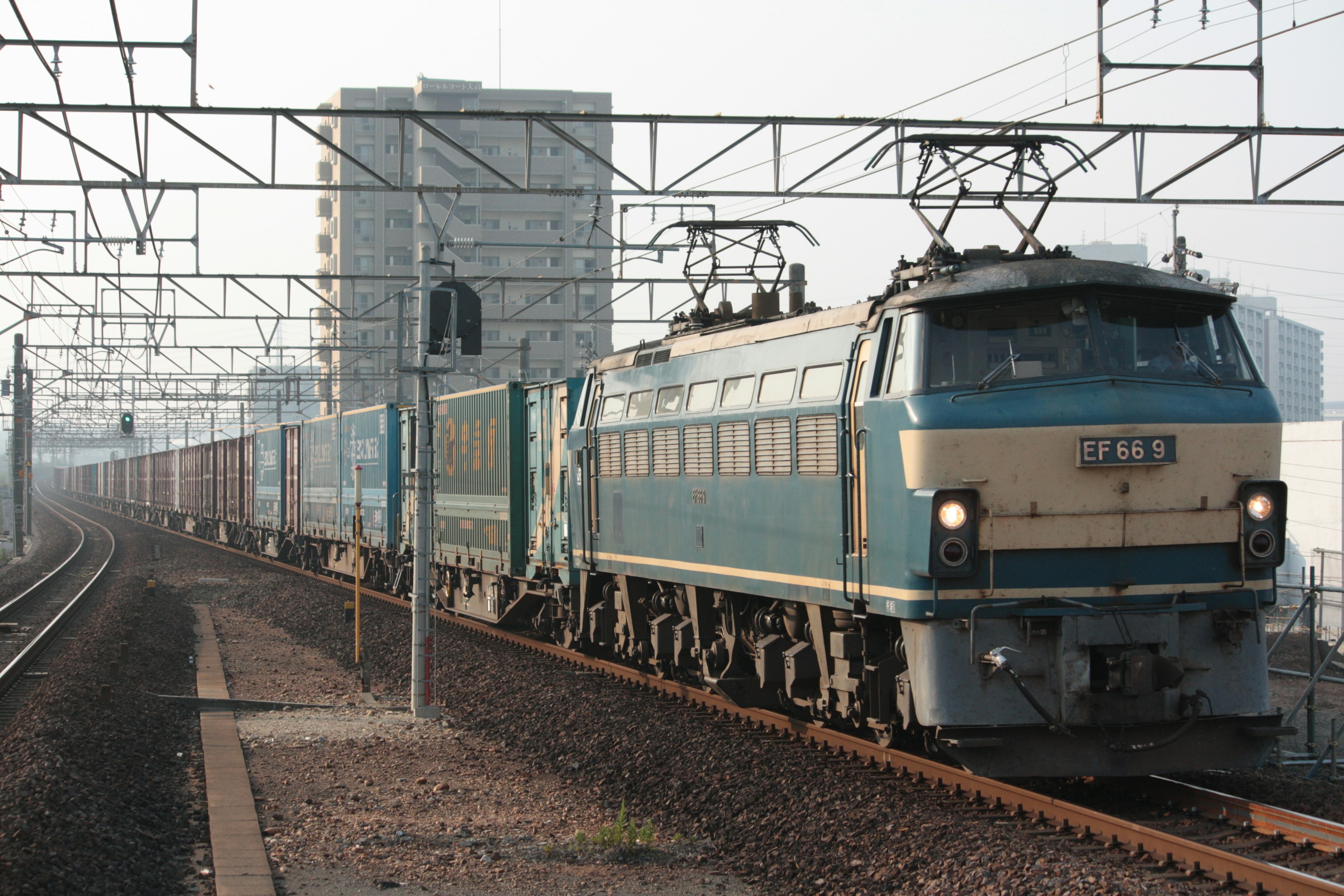 Locomotora eléctrica azul tirando un tren de carga en las vías