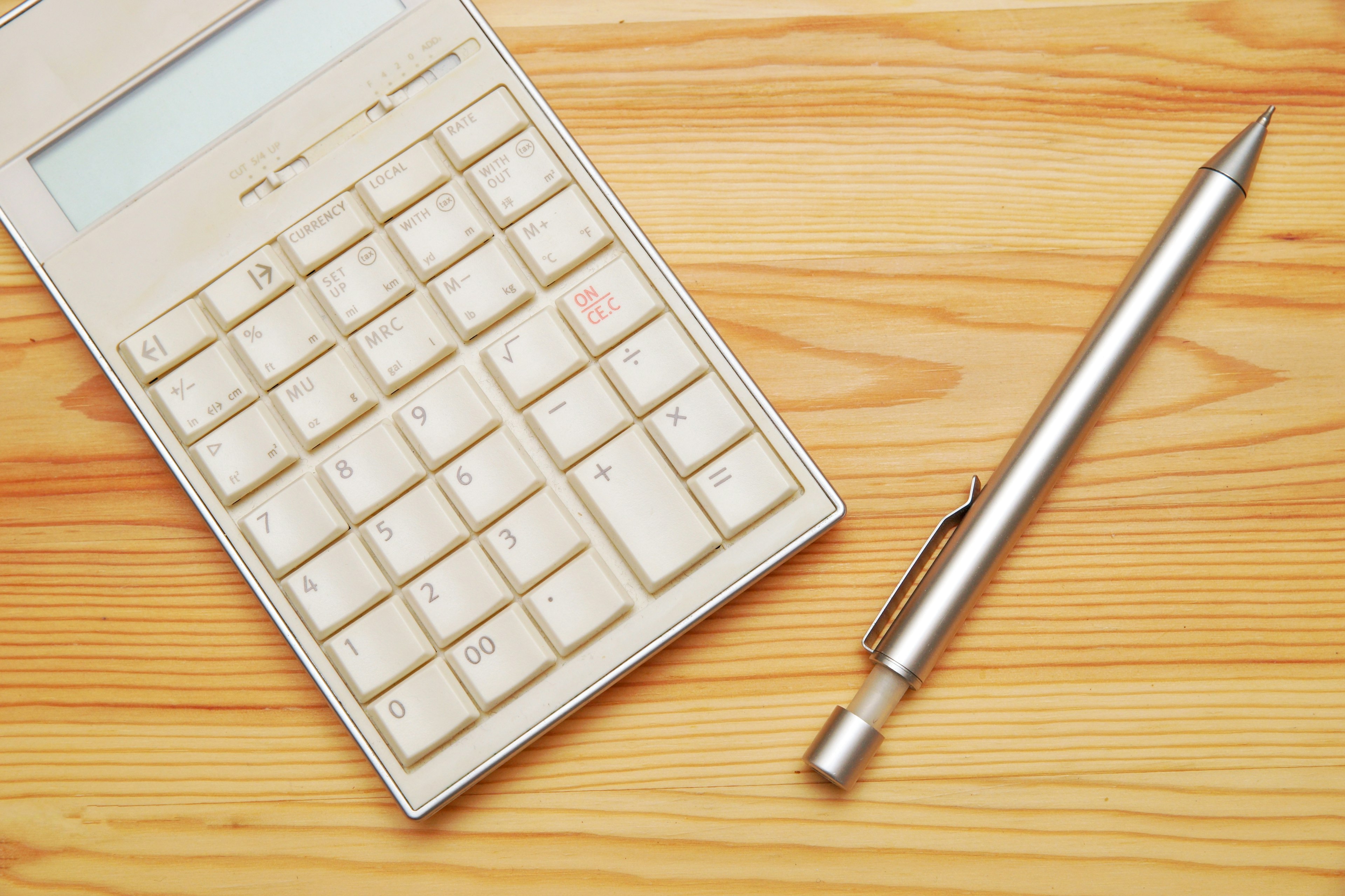 A calculator and a pen on a wooden table