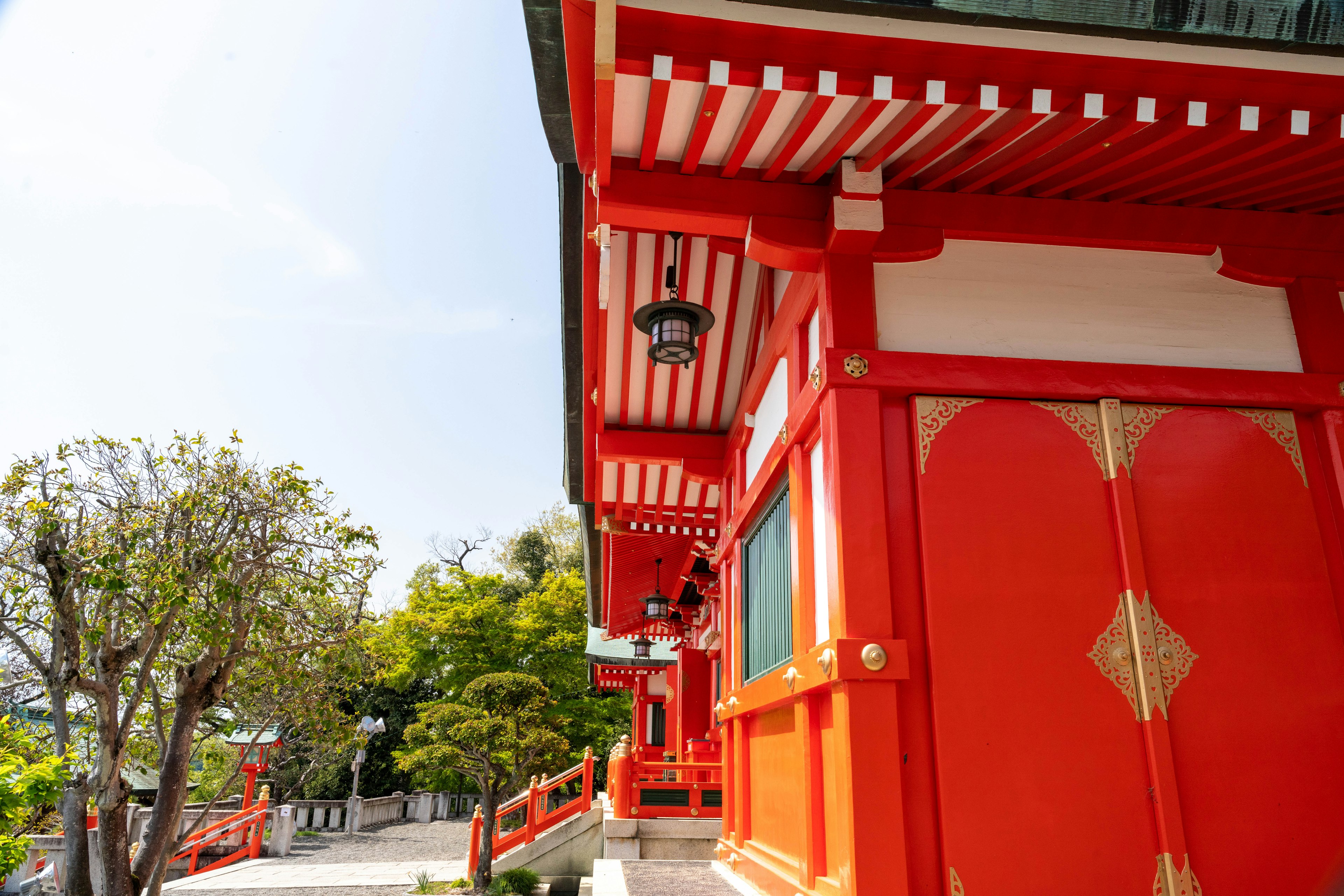 Vibrant red building with white roof of a temple surrounded by greenery and blue sky