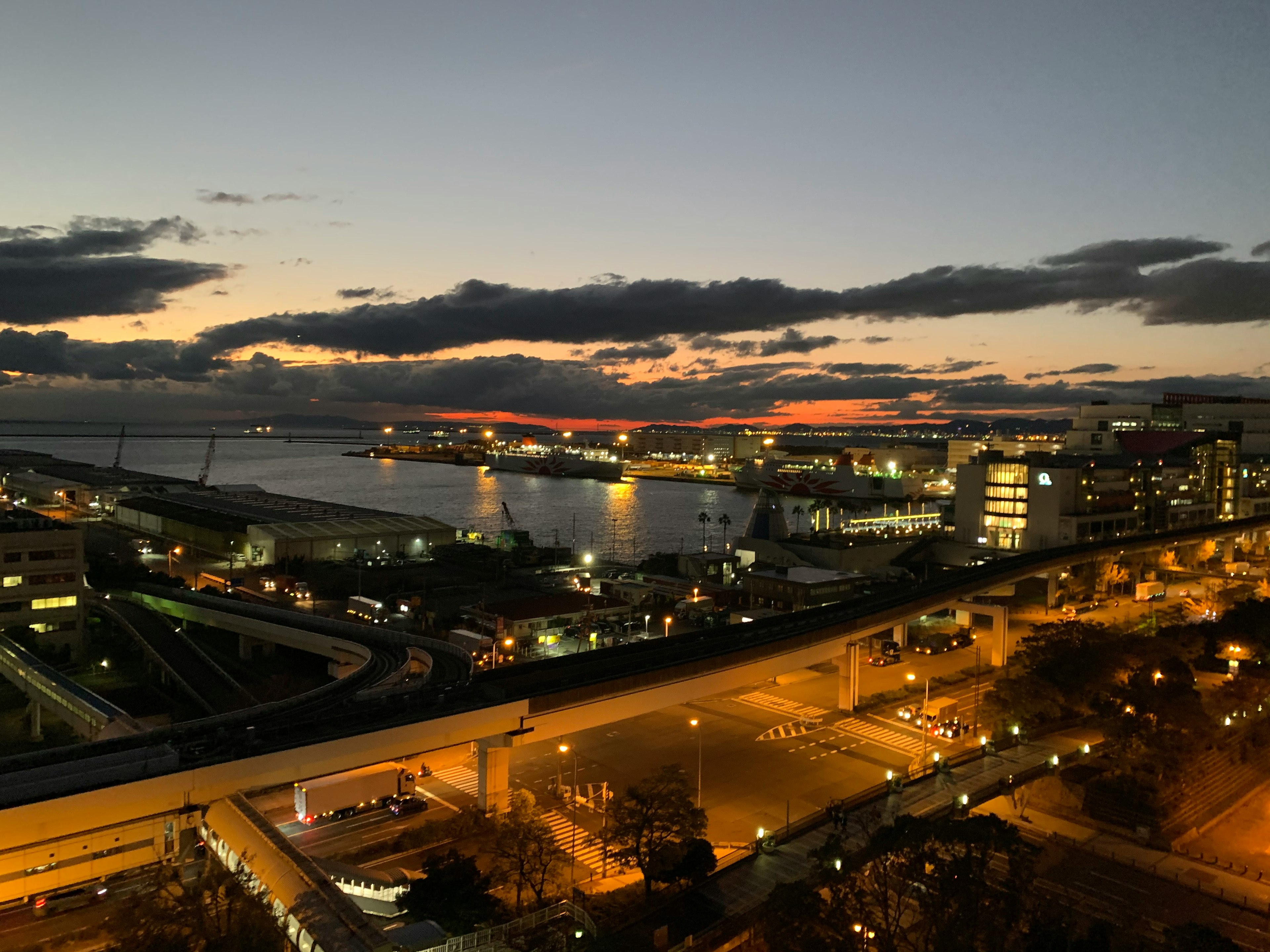 夕暮れ時の港の景色に映る街の明かりと雲