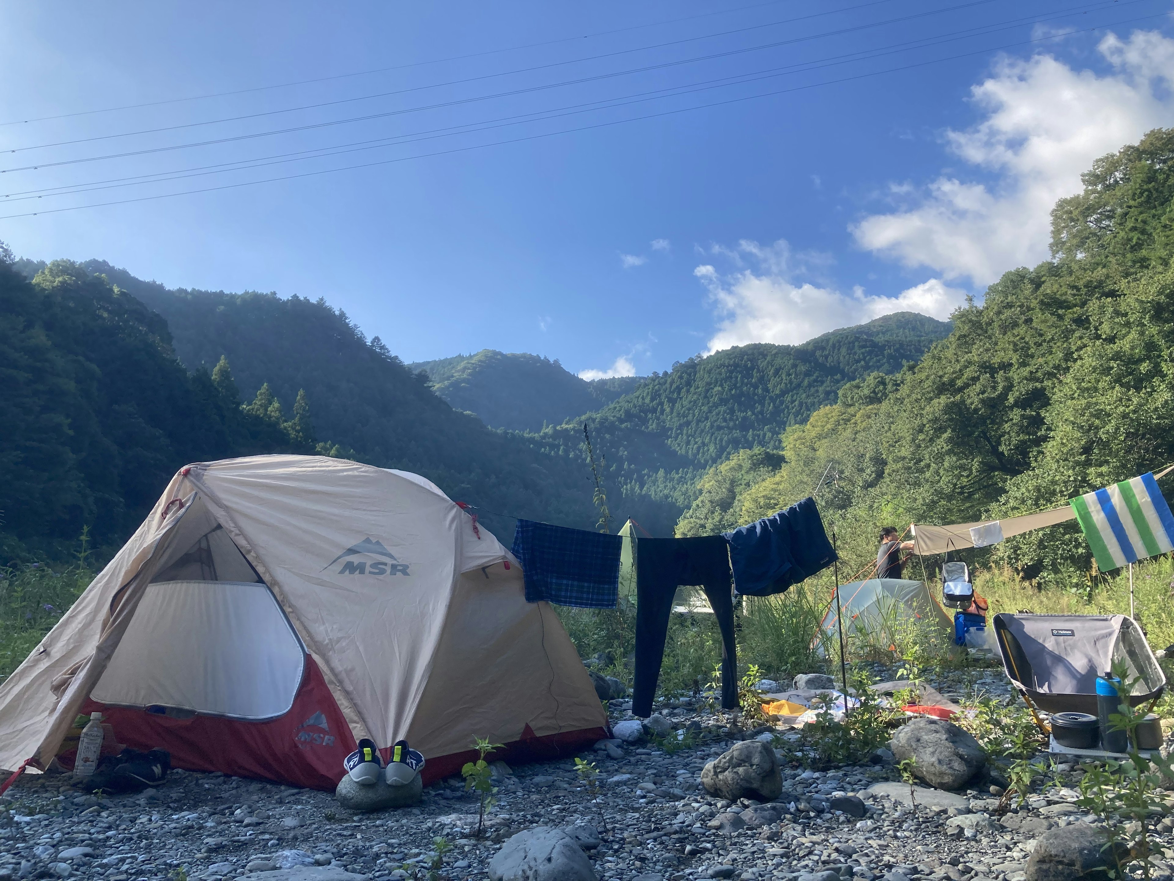 一个被山环绕的露营地，有一个帐篷和晾晒的衣物