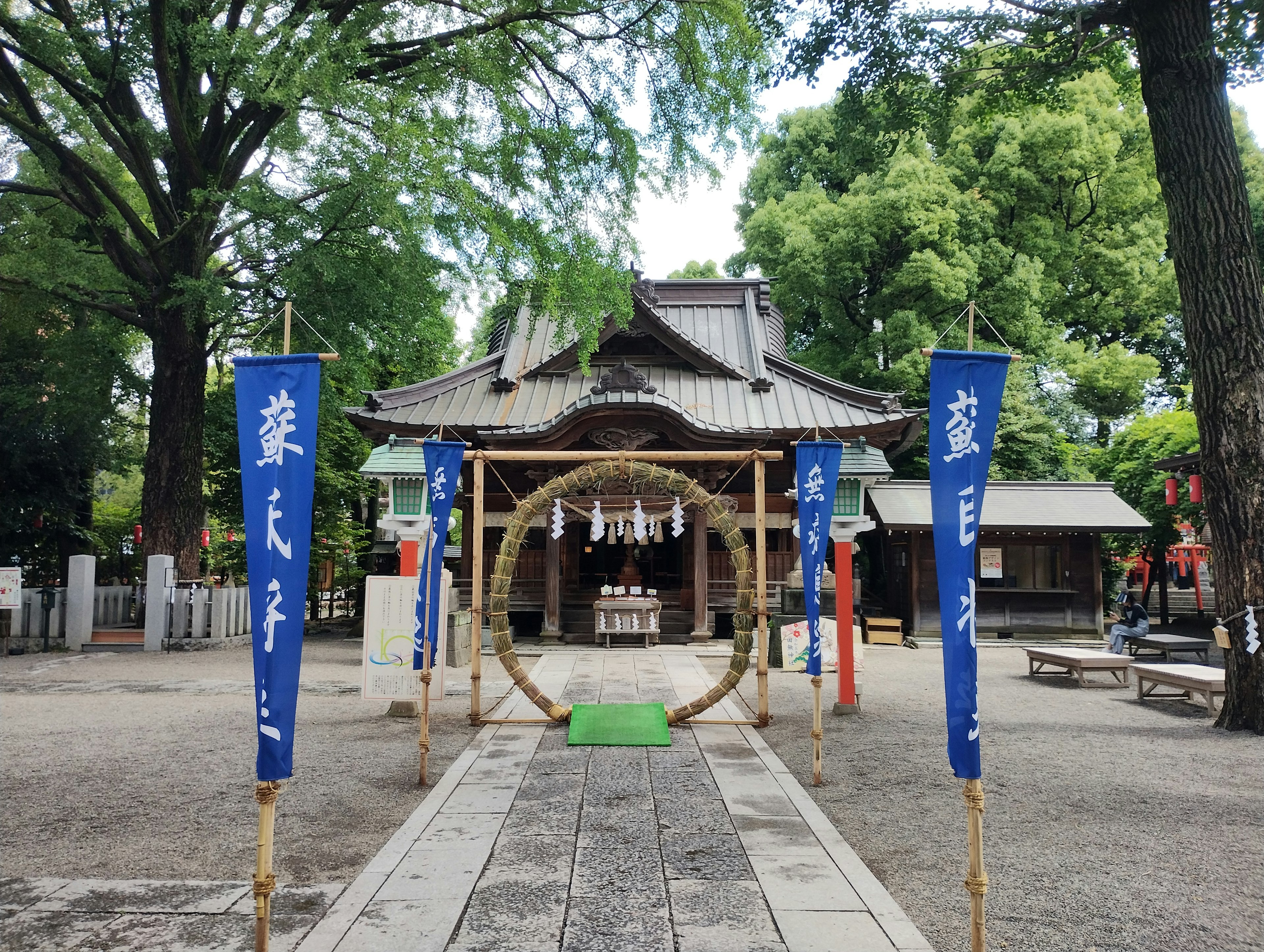 Entrance of a shrine with blue banners and a sacred rope in the center