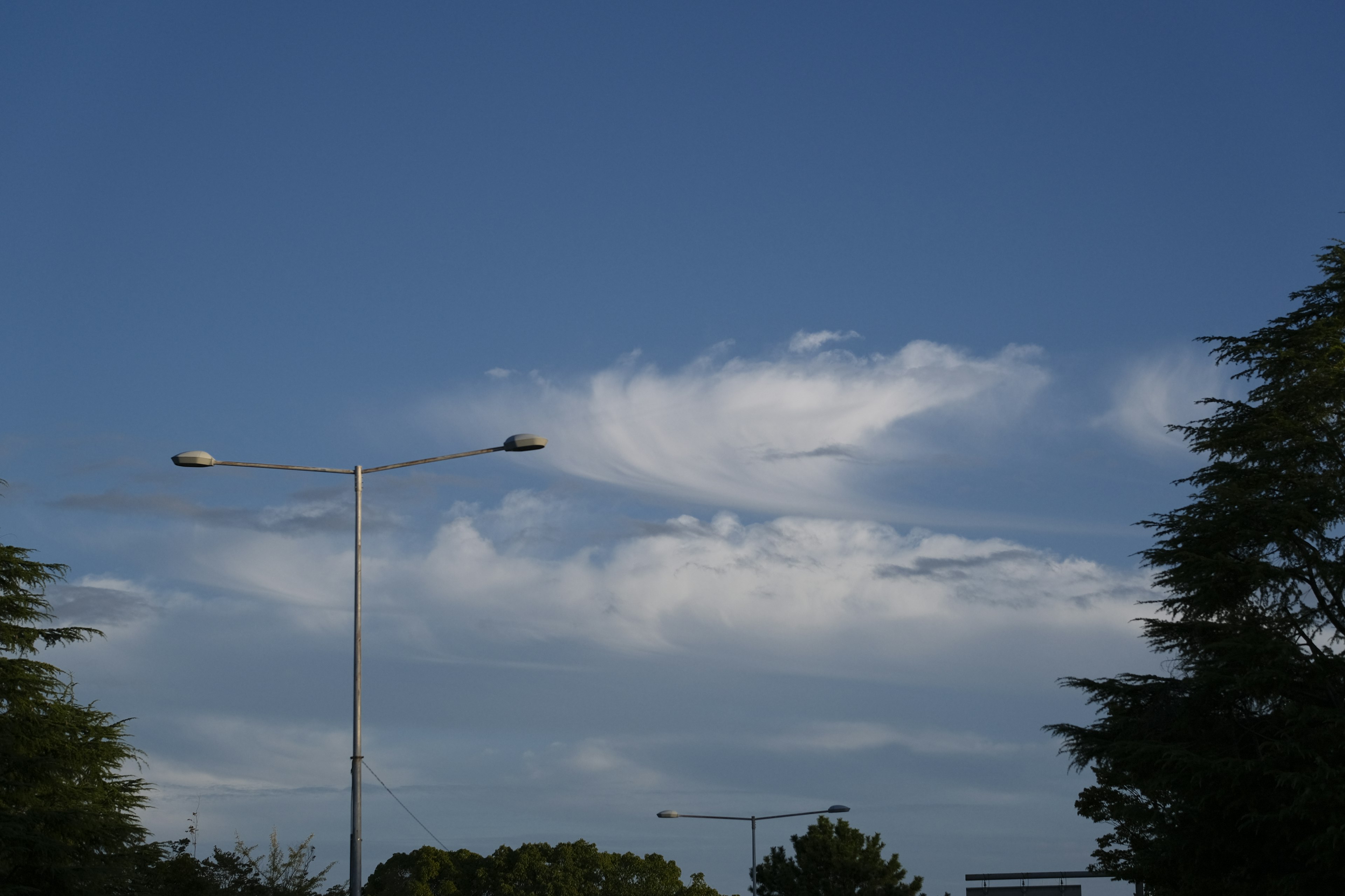 Awan putih melayang di langit biru dengan lampu jalan