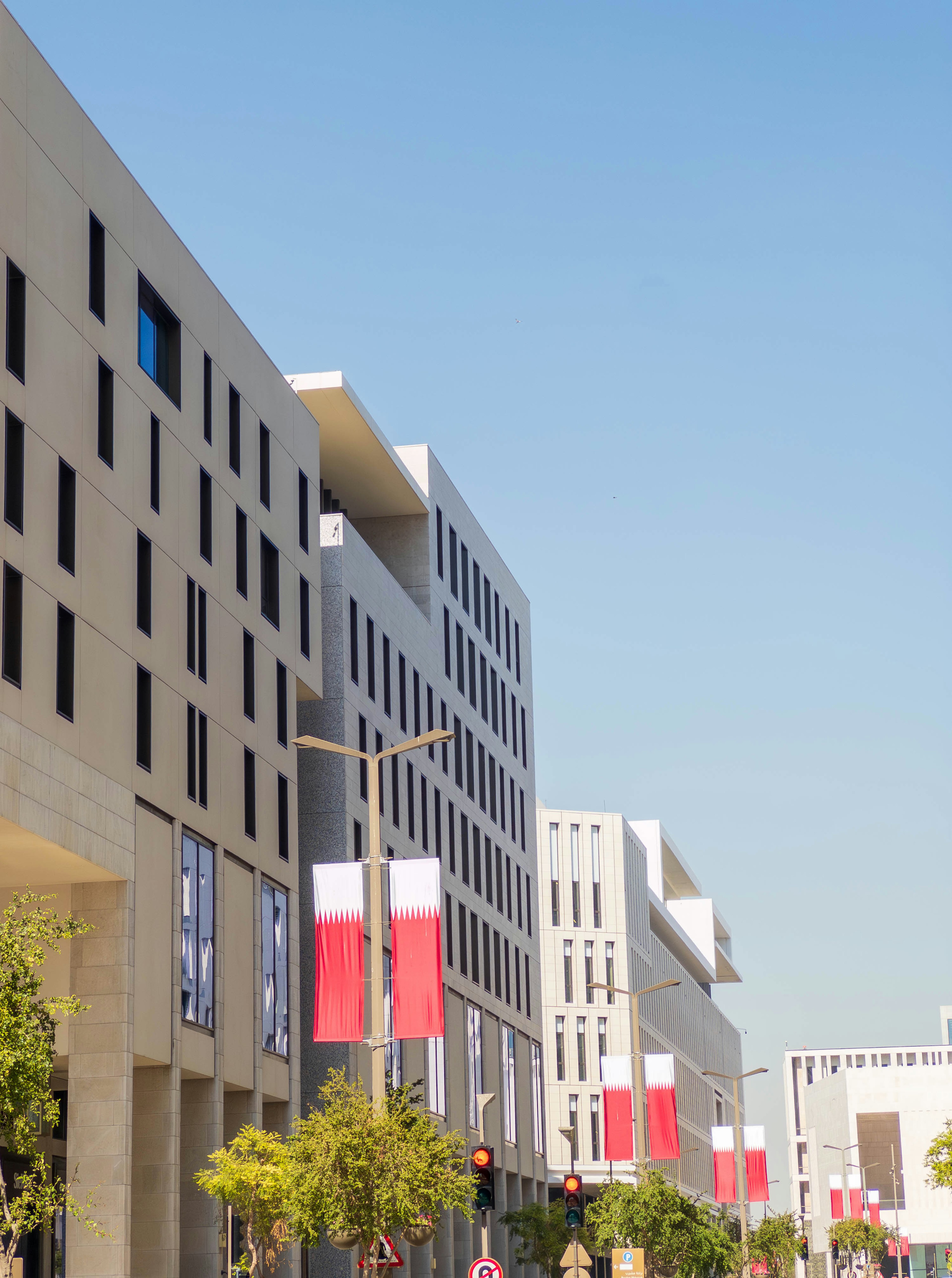 Modern buildings lined up under a clear blue sky with Polish flags