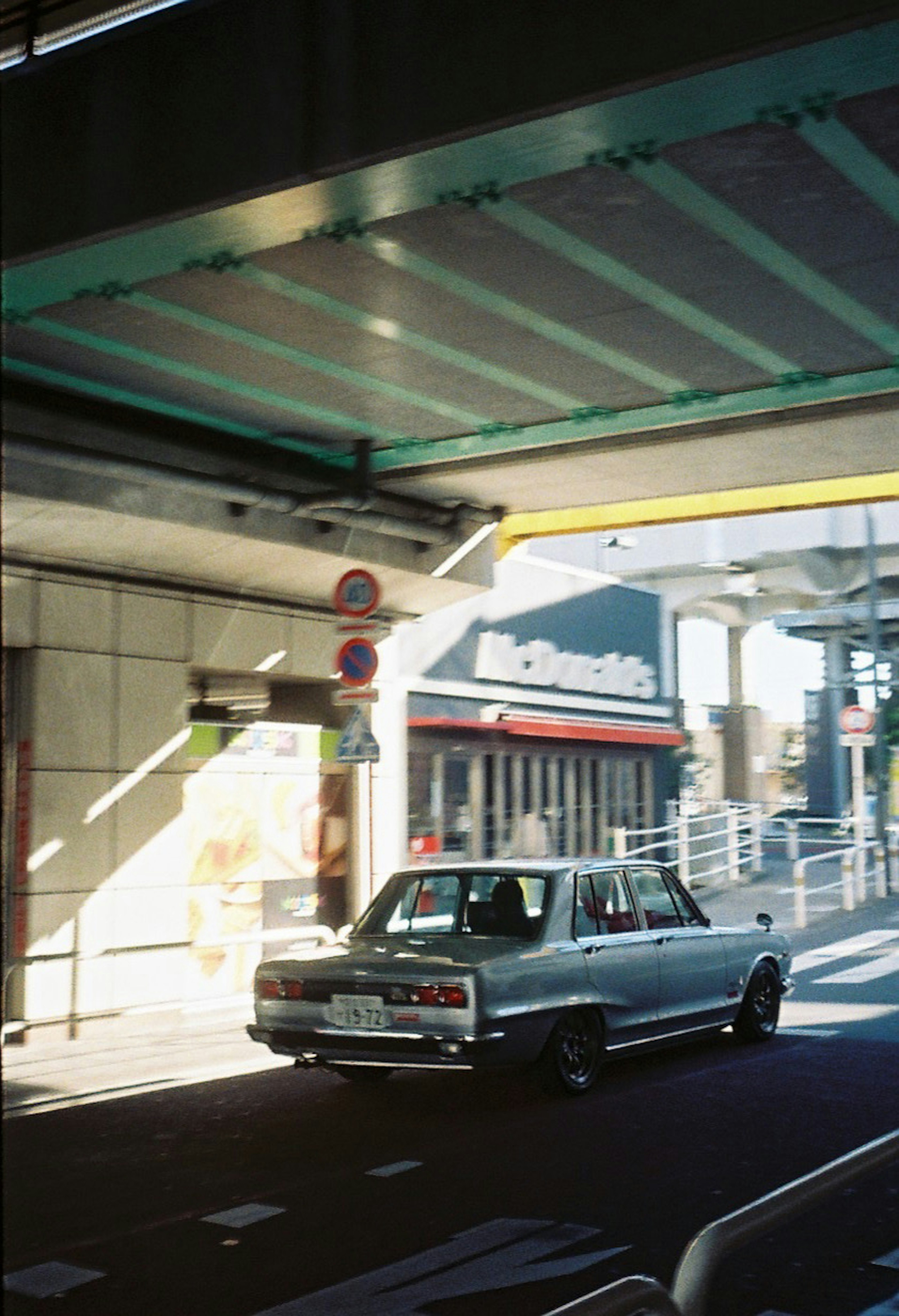 街中の道路を走る古い車と近くの店舗の風景