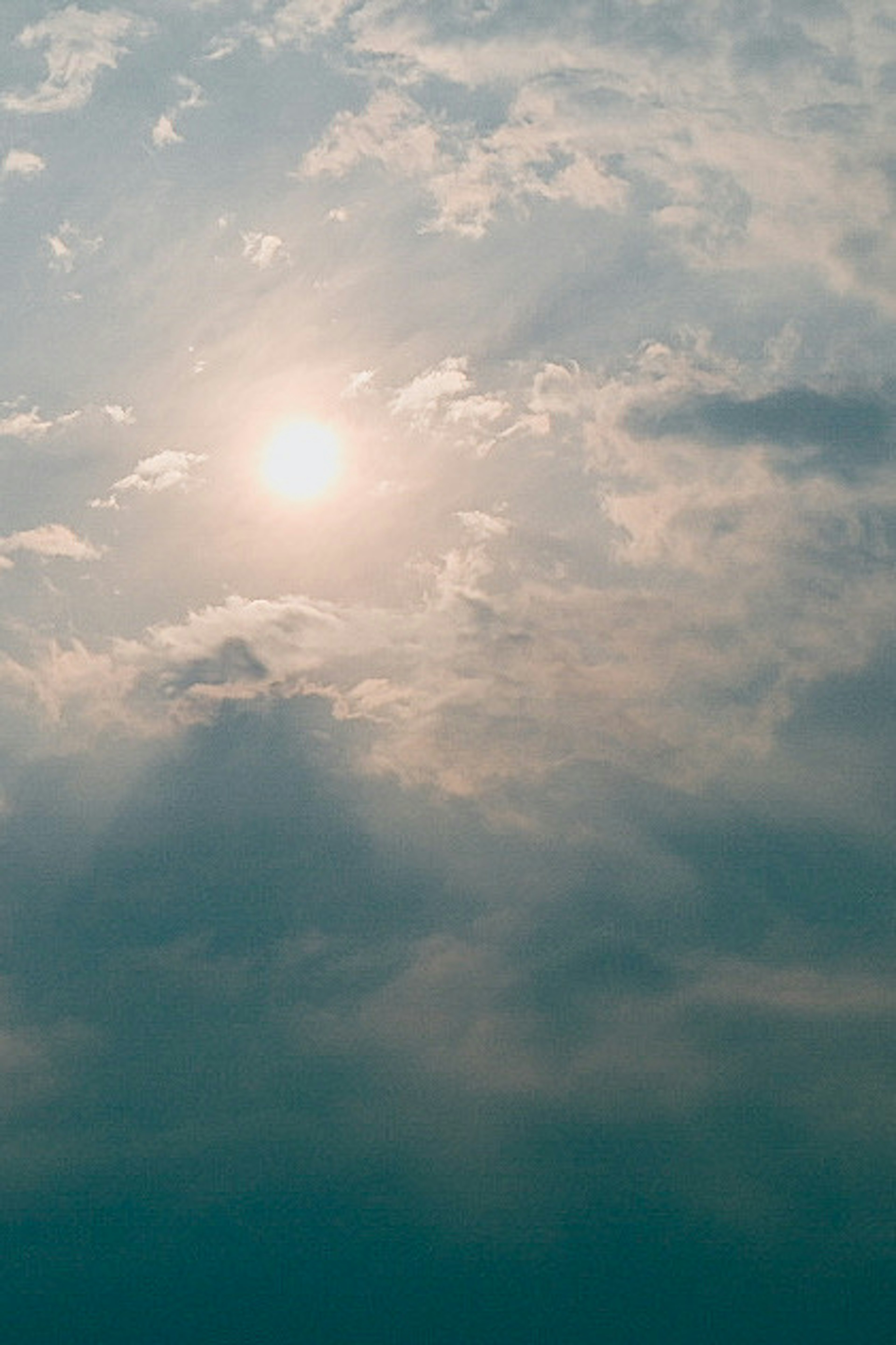 Calm landscape with clouds and sun in a blue sky