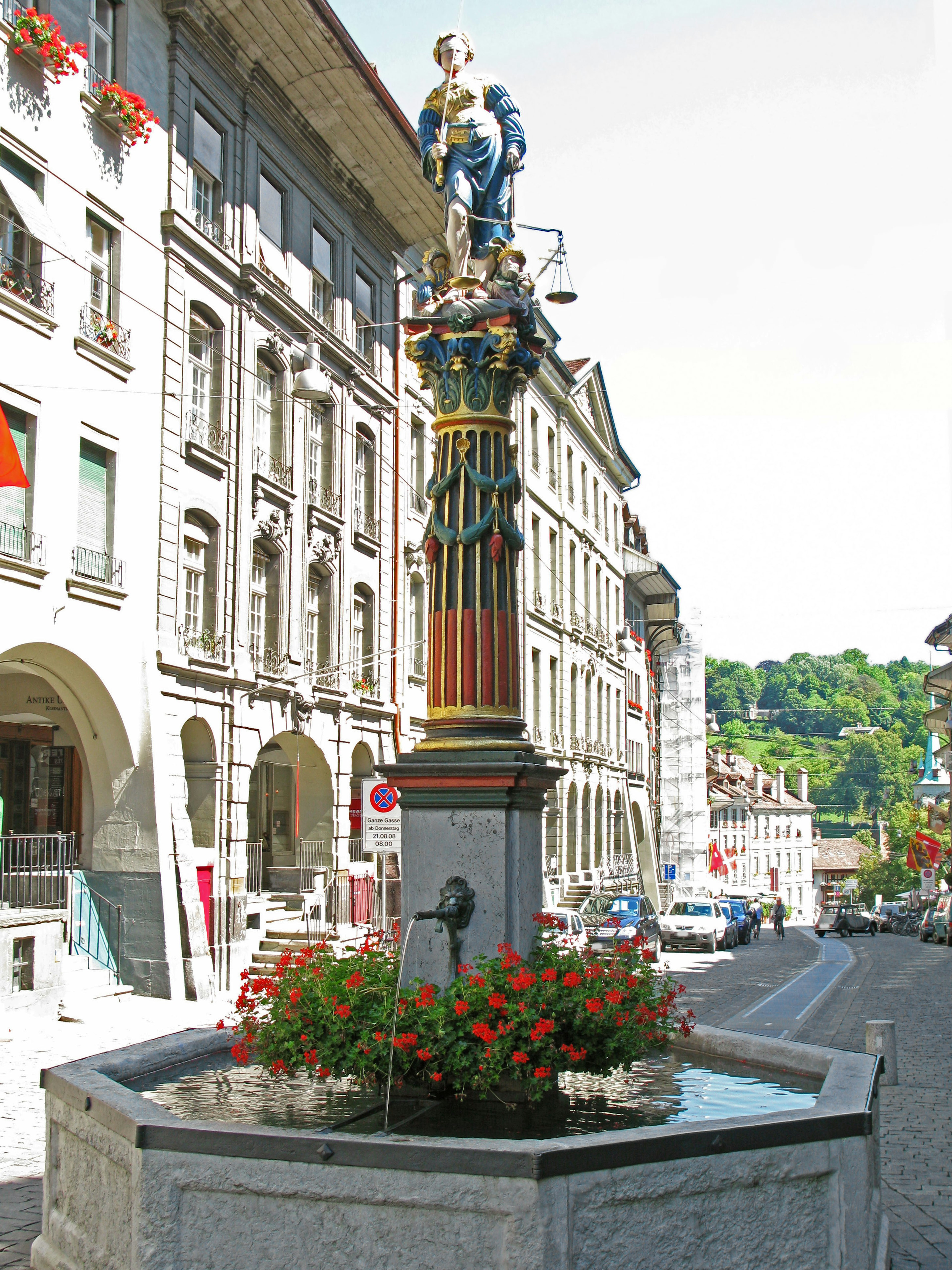 Vue de rue avec une fontaine colorée et des fleurs vibrantes