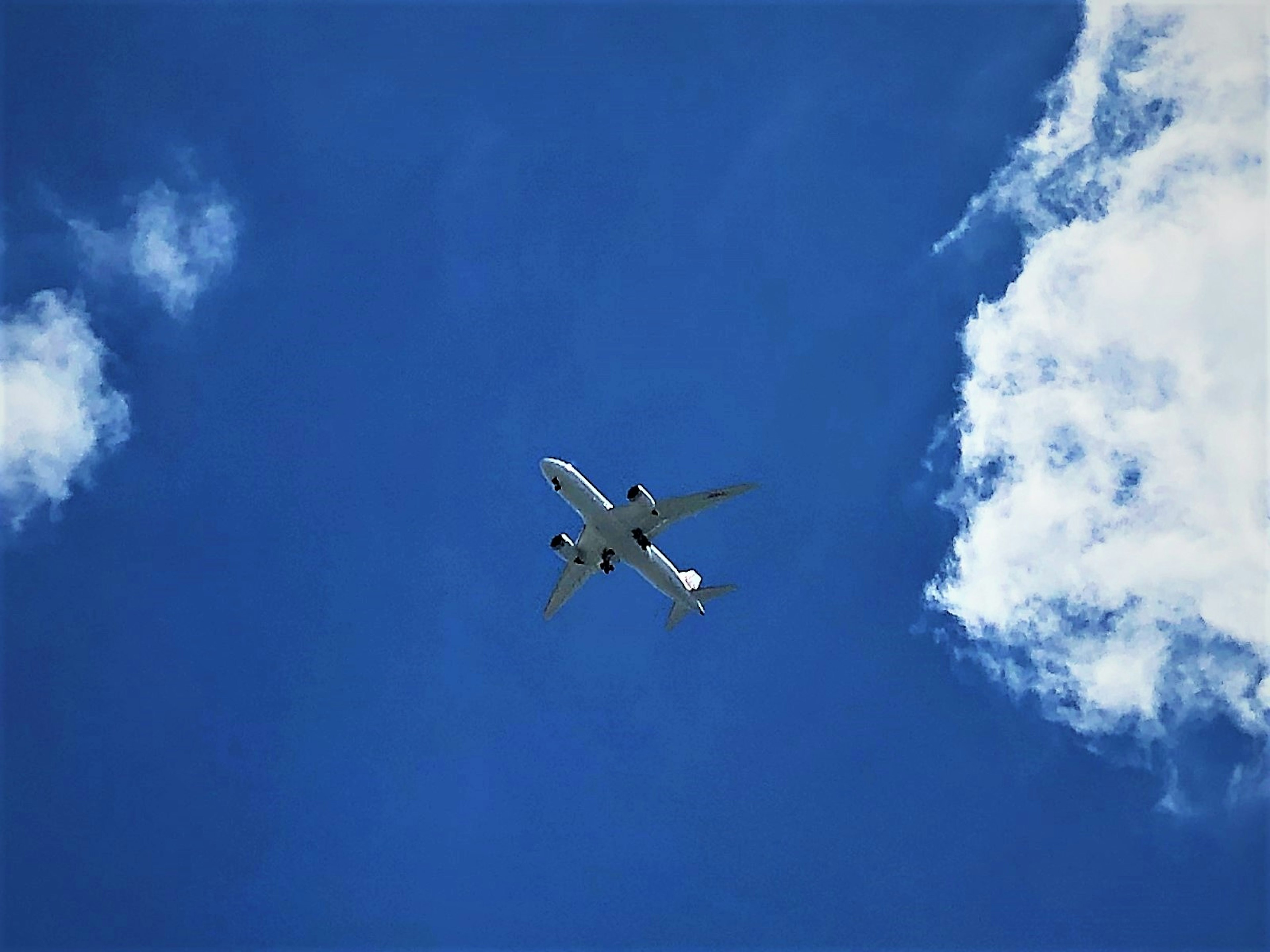 Airplane flying in a clear blue sky with white clouds