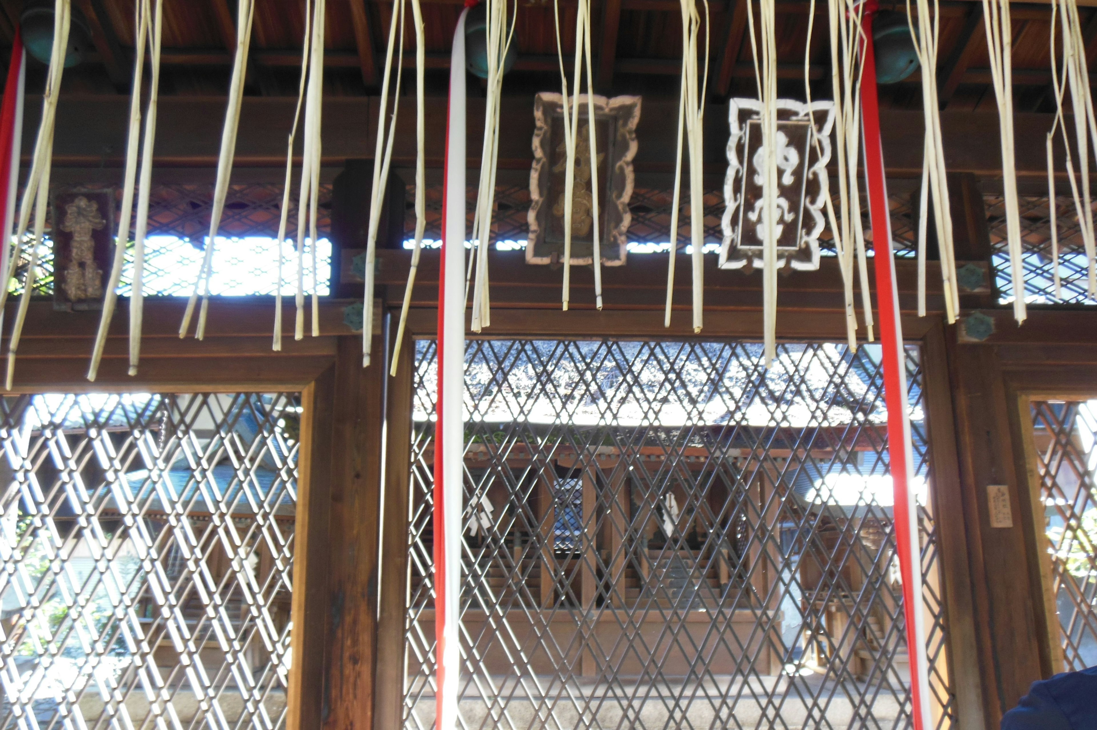 Interior of a shrine featuring hanging thin white ribbons and traditional patterned objects