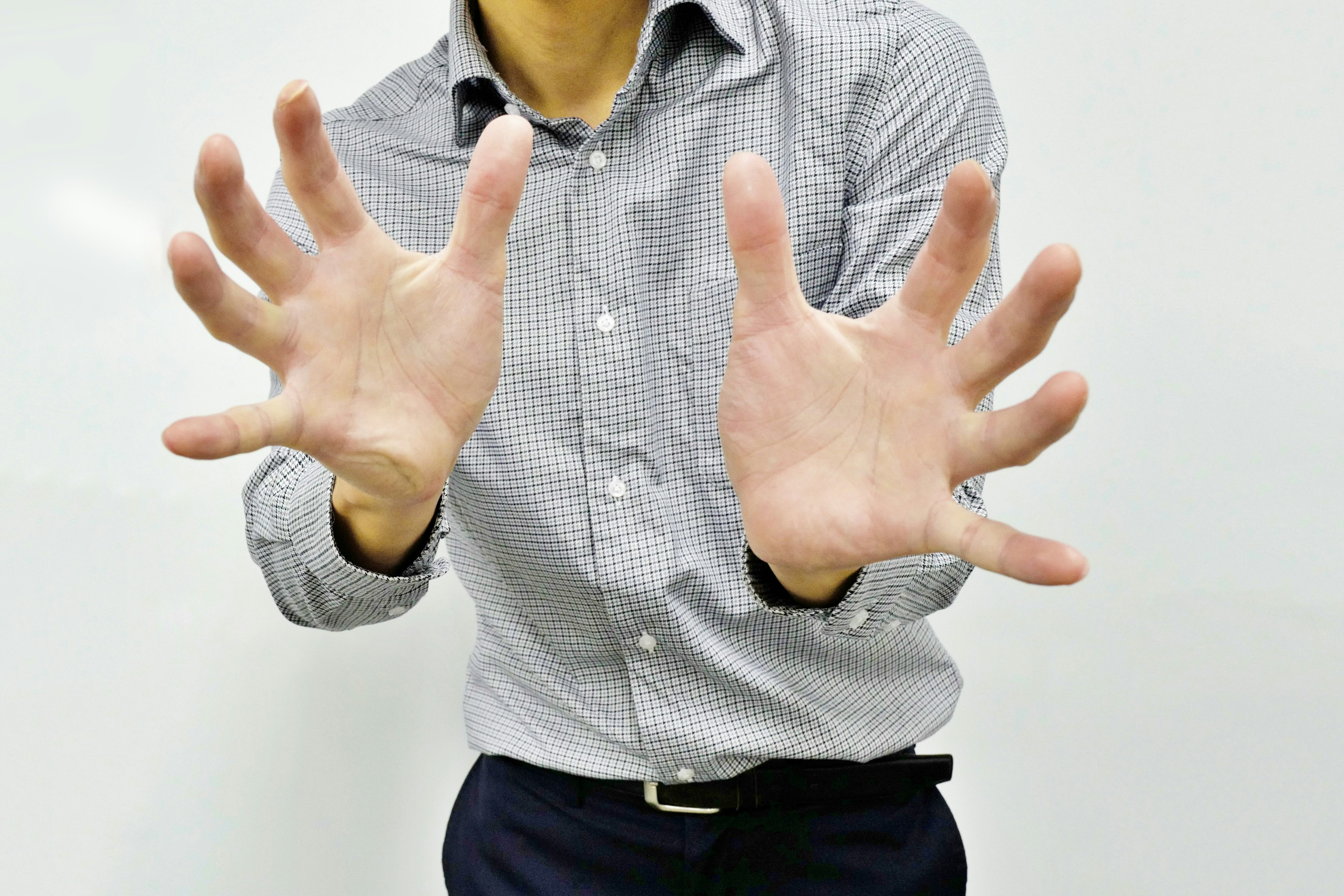 Un hombre con una camisa a cuadros extendiendo ambas manos hacia adelante