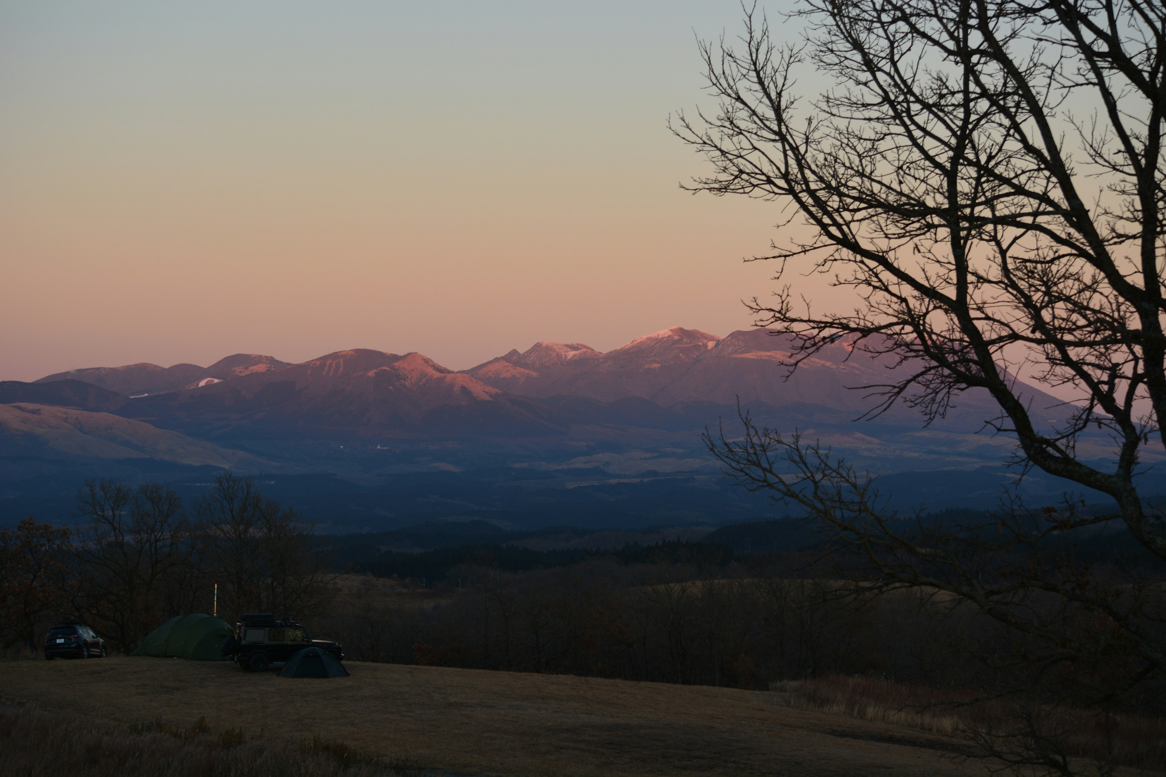 夕焼けの山々と木のシルエットが映える風景