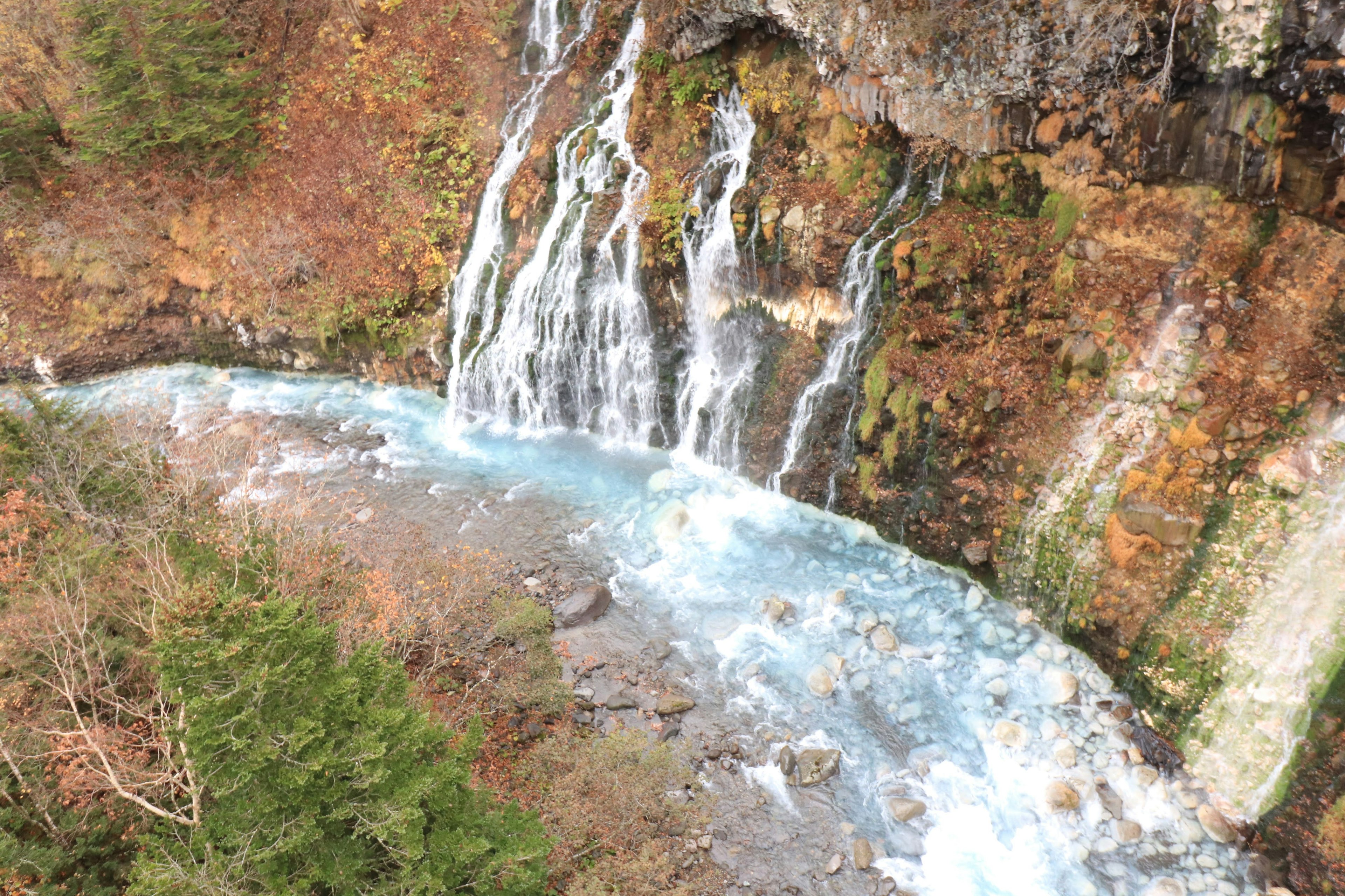 Pemandangan indah air terjun yang mengalir ke sungai biru